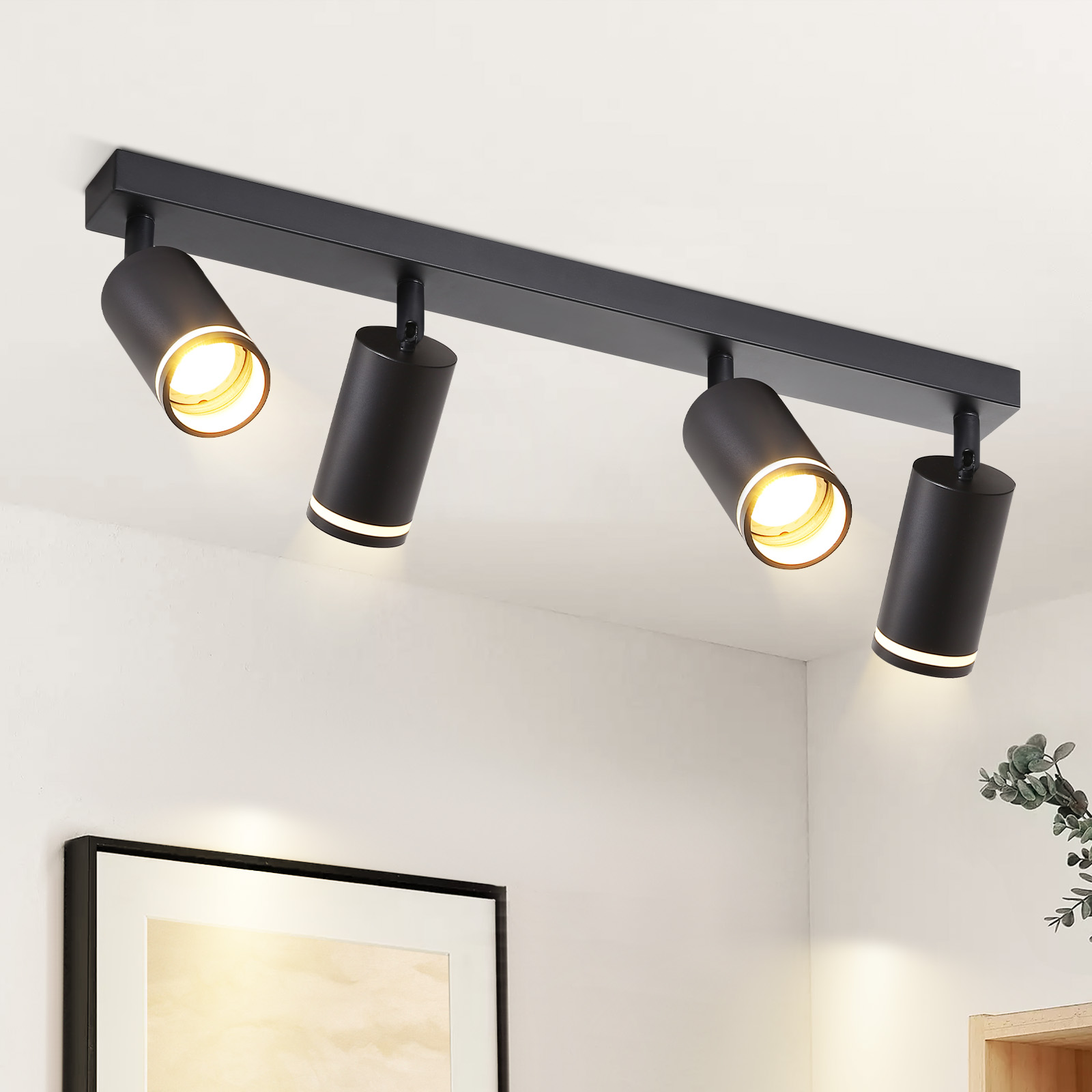 Czarna lampa sufitowa z czterema regulowanymi reflektorami. Światła są skierowane w dół.