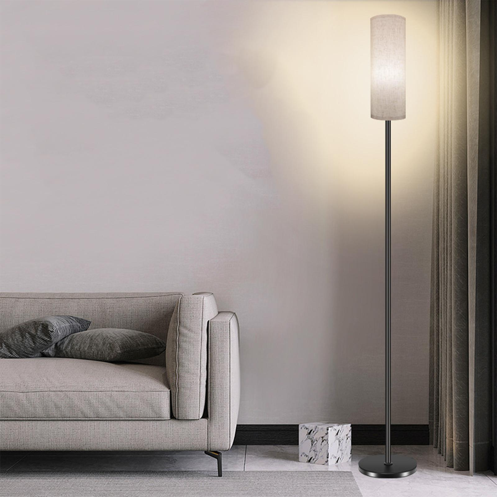 Schwarze Stehlampe mit beigem Schirm neben einem Sofa im Raum.