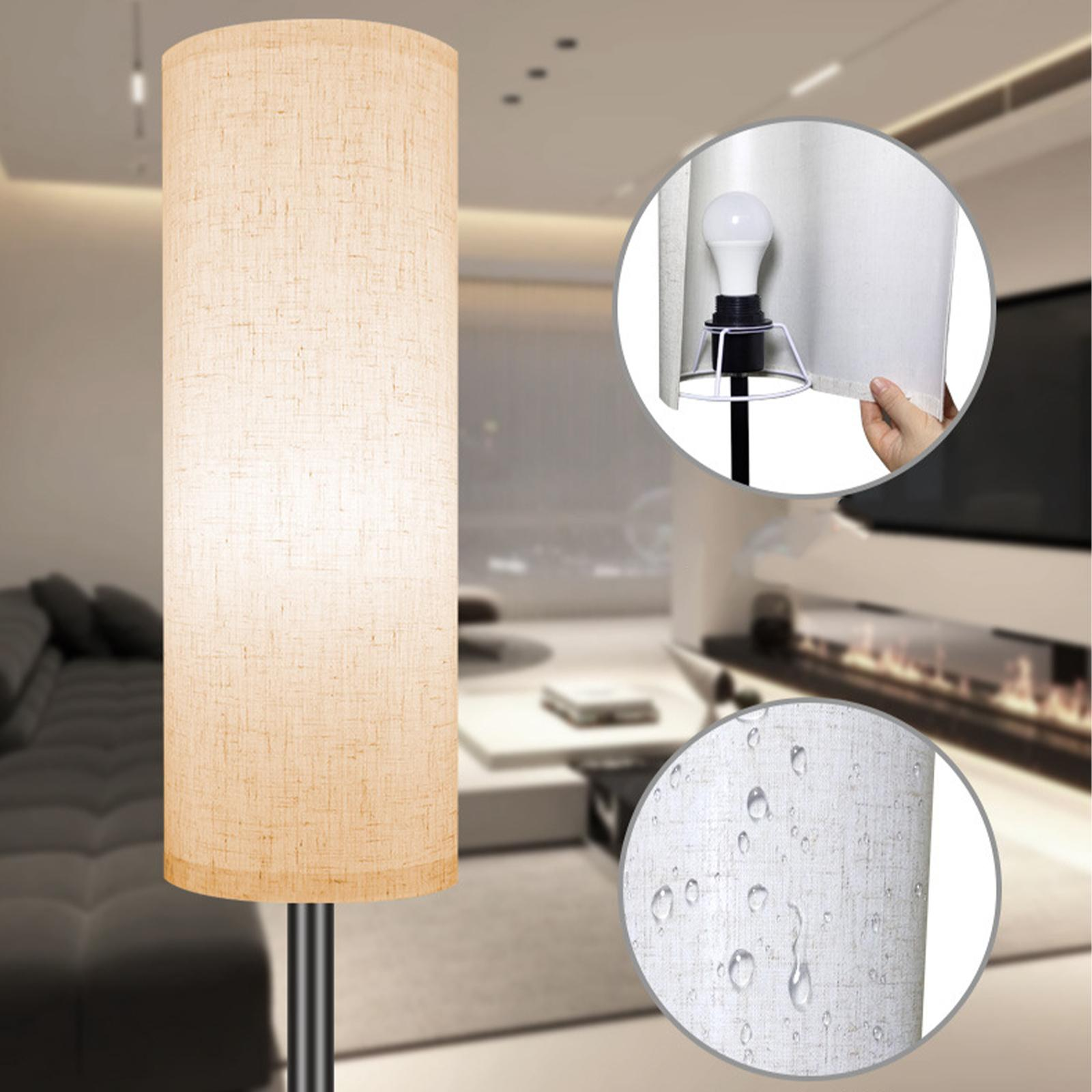 Stehlampe mit beigem Schirm und schwarzem Ständer. Details umfassen Glühbirne.