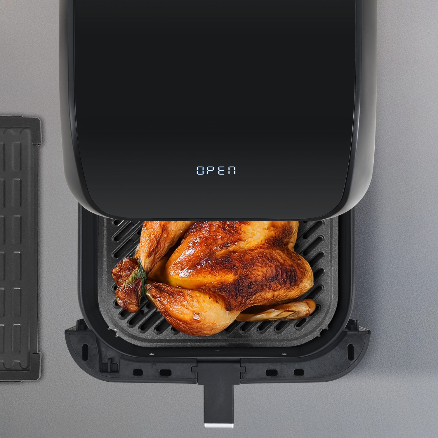 Ein gebratenes Huhn in einer schwarzen Heißluftfritteuse. Die Tür ist geöffnet, und die Anzeige lautet 'OPEN'.