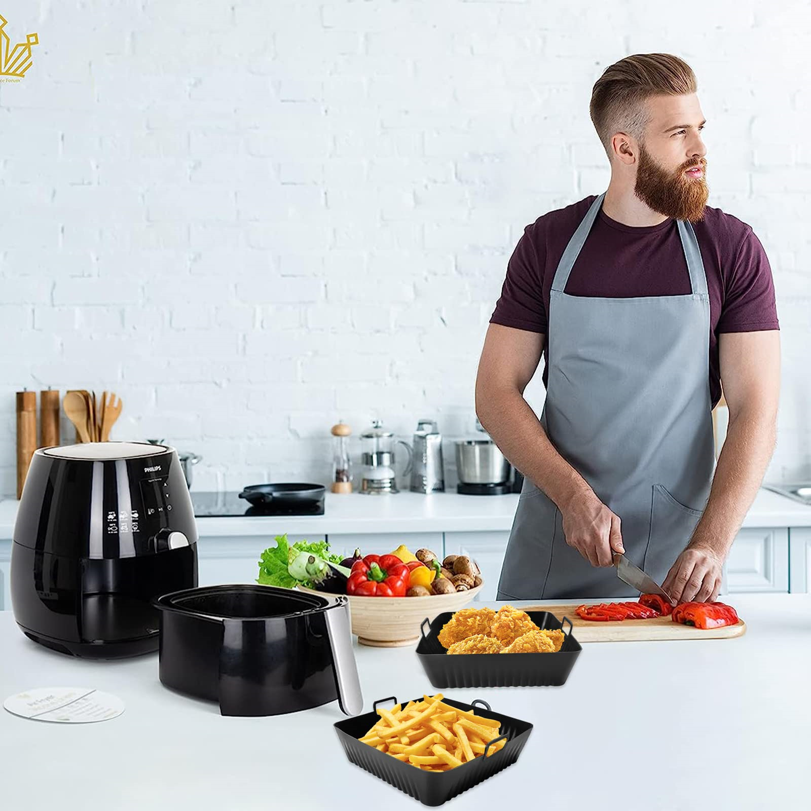 Ein Mann in einer Küche bereitet Essen zu. Eine Heißluftfritteuse und Zubehör stehen auf der Theke. Essen ist in den schwarzen Körben.