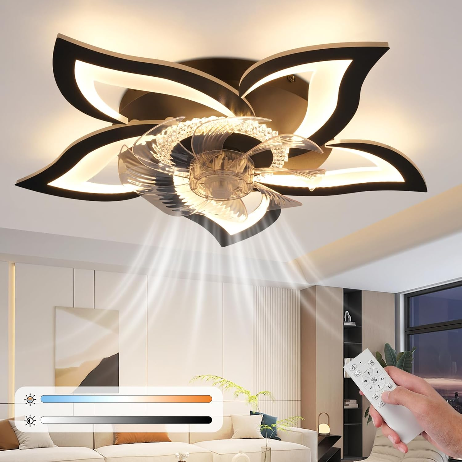 Un ventilatore a soffitto a forma di fiore con luci illumina un moderno spazio abitativo. Un telecomando è nella mano di qualcuno.