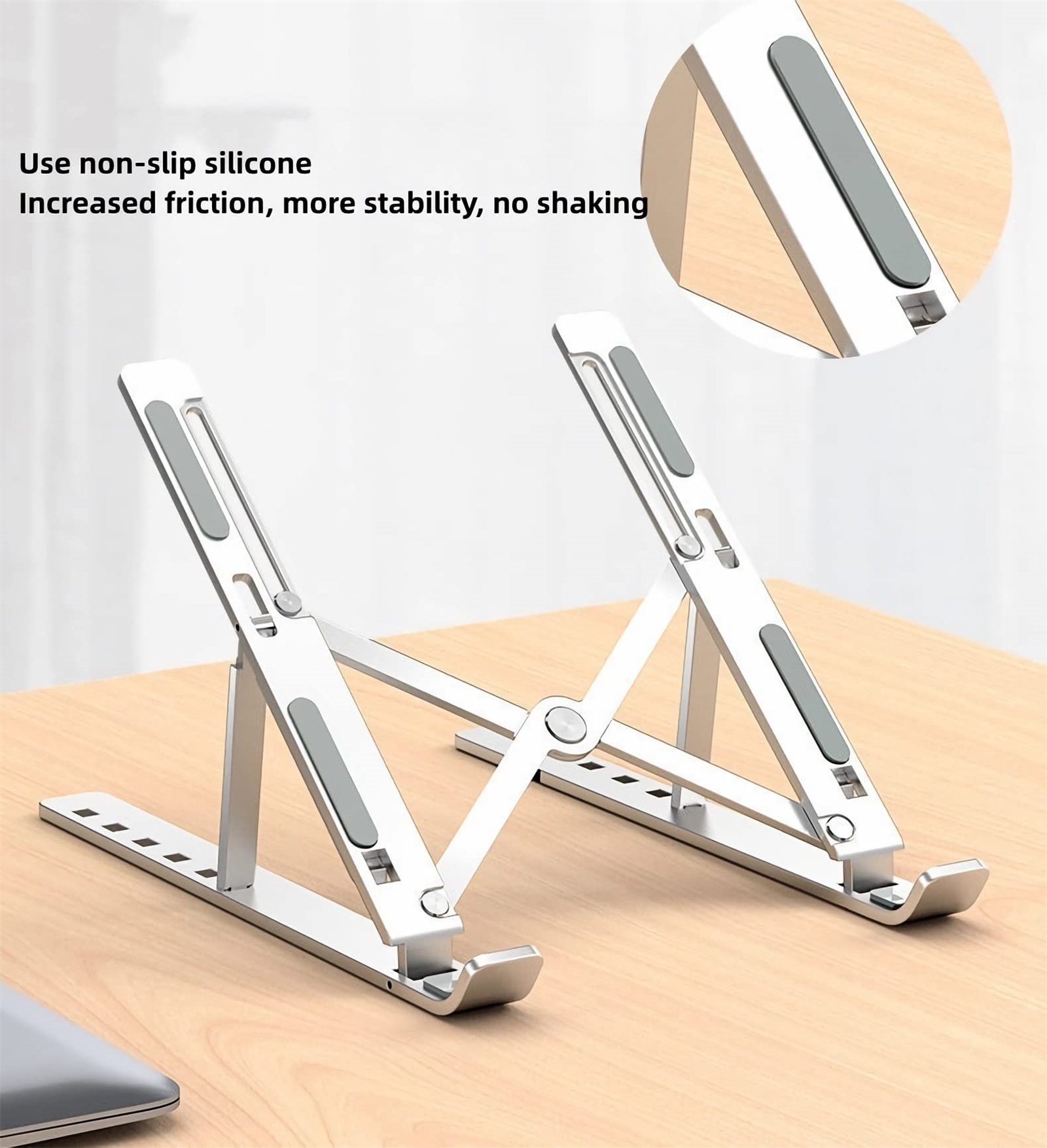 Silberner, zusammenklappbarer Laptopständer auf einer Holzoberfläche, schräge Ansicht, mit Silikonpads für Stabilität.
