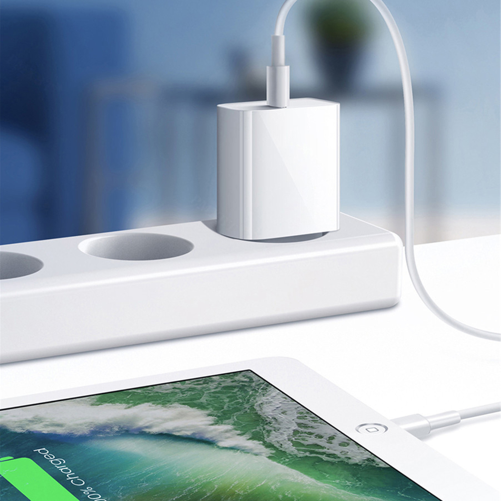 Ladegerät in eine Wandsteckdose gesteckt, das ein Tablet mit vollem Akku mit Strom versorgt und die Ladeeffizienz demonstriert.