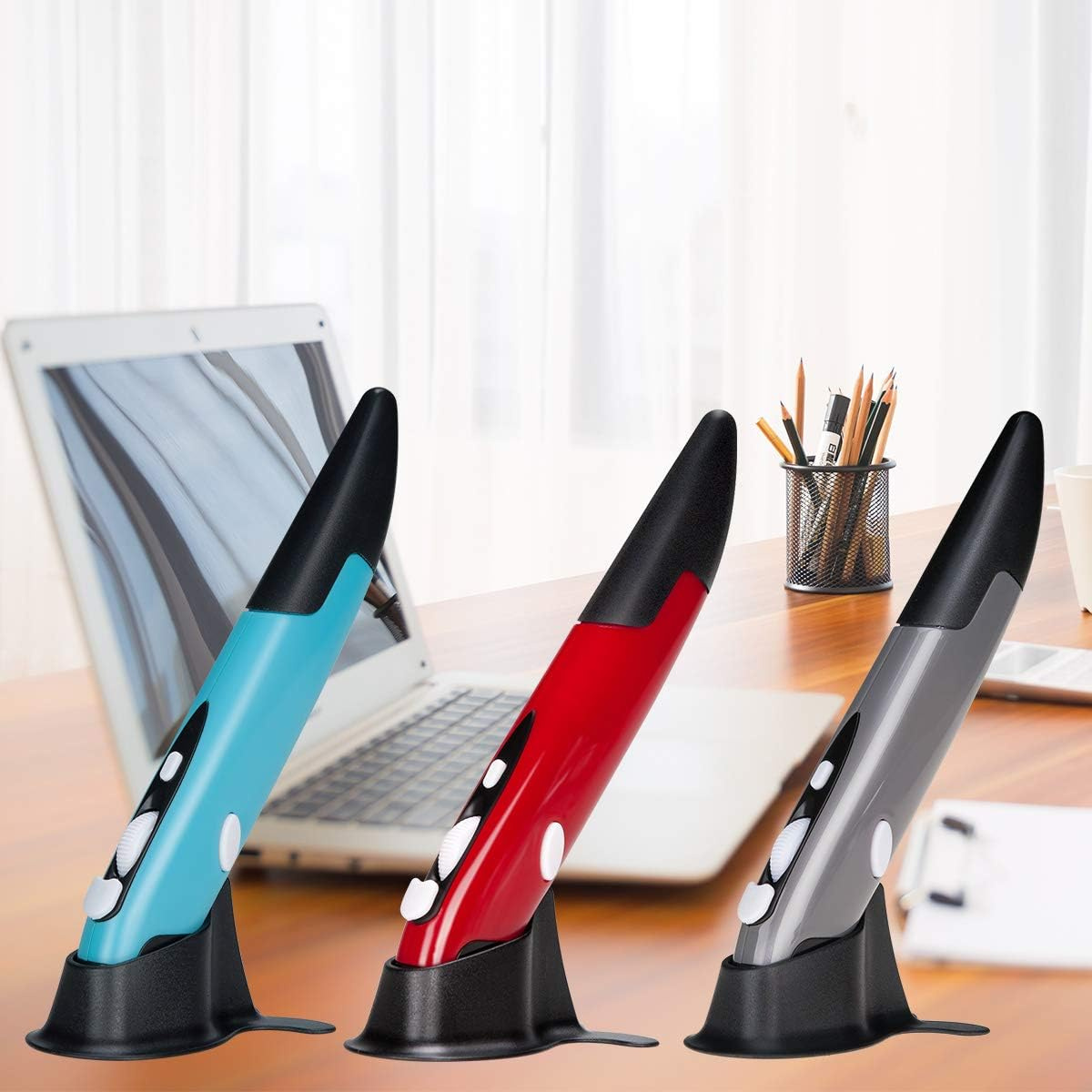 Drei Stiftmäuse in Blau, Rot und Grau stehen auf einem Schreibtisch vor einem Laptop und Schreibtischzubehör.