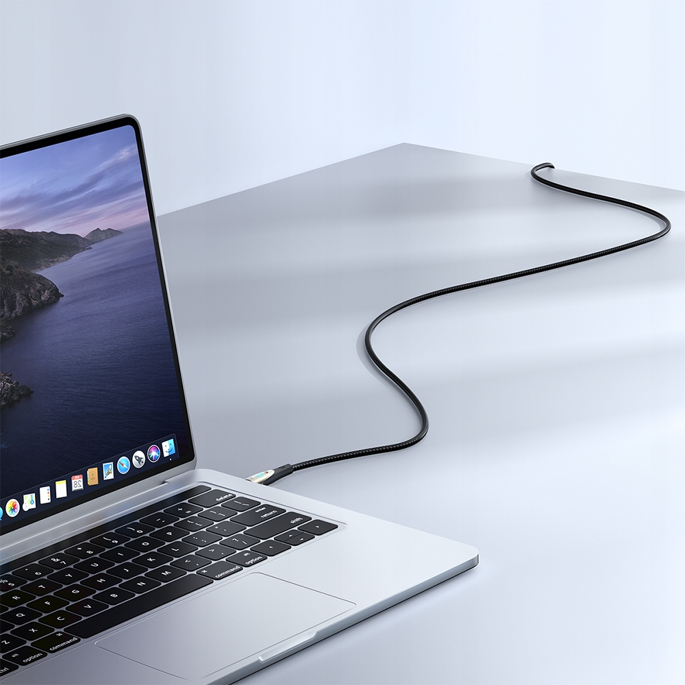 Ein Ladekabel, das einen Laptop auf einem weißen Schreibtisch verbindet, Seitenansicht.