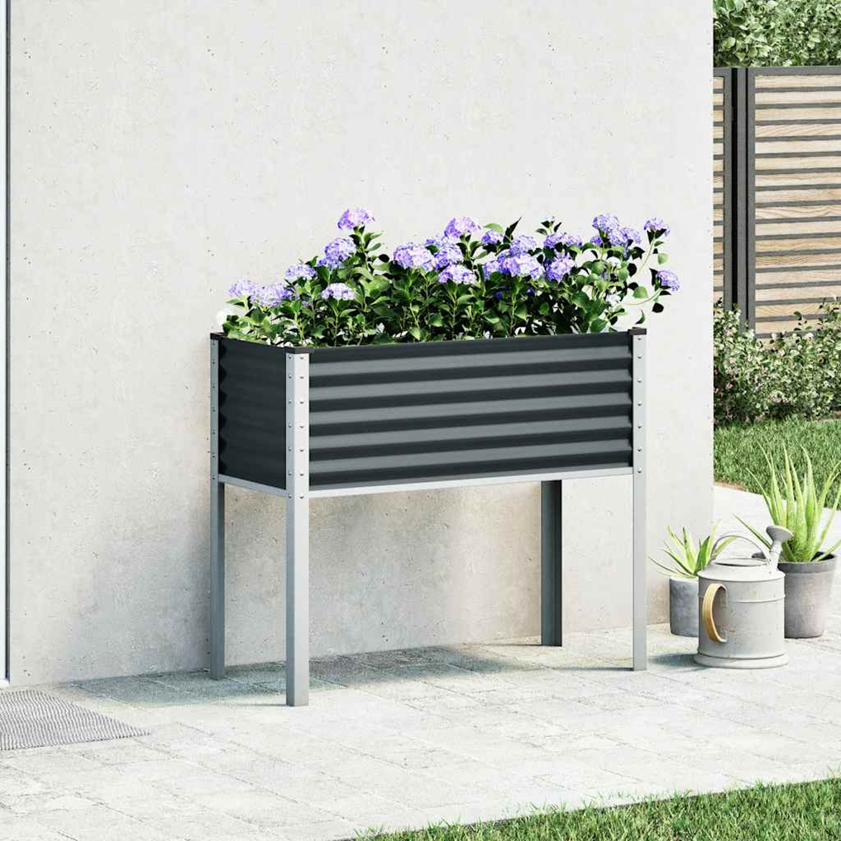 Un'aiuola rialzata con fiori viola e bianchi accanto a un edificio e altre piante.