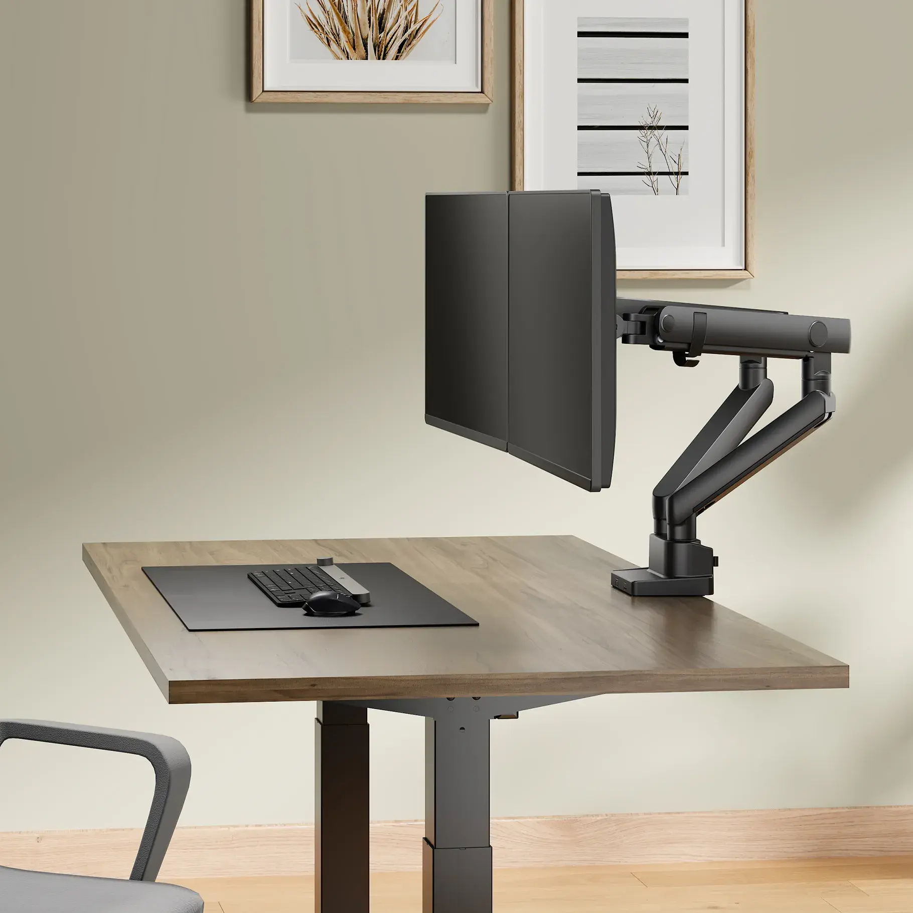 Deux moniteurs sont montés sur un bras de moniteur double noir, positionnés sur un bureau avec un clavier, une souris et des accessoires.