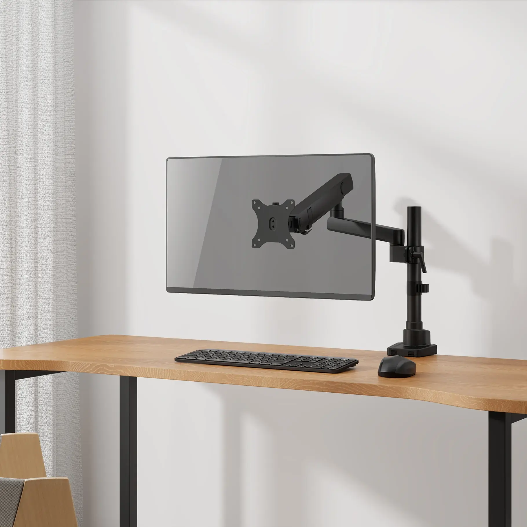Un bras de moniteur noir maintient un moniteur au-dessus d'un bureau. Le bureau est en bois.