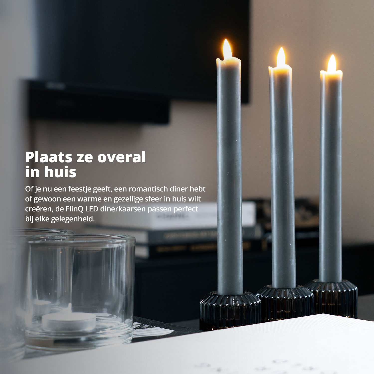 Three gray candles in black holders are displayed on a black table.