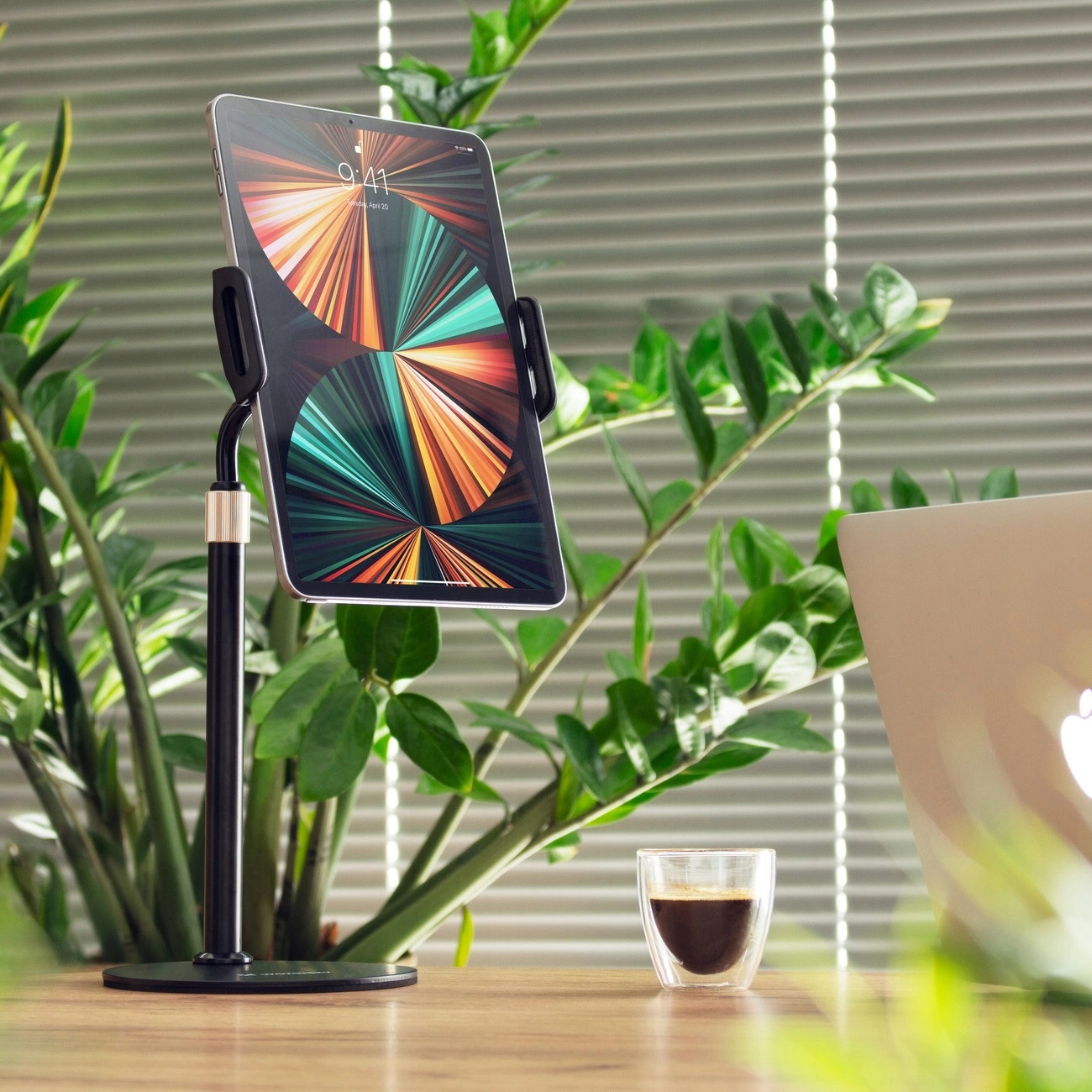 Czarny stojak na telefon z tabletem. Po prawej szklanka kawy.