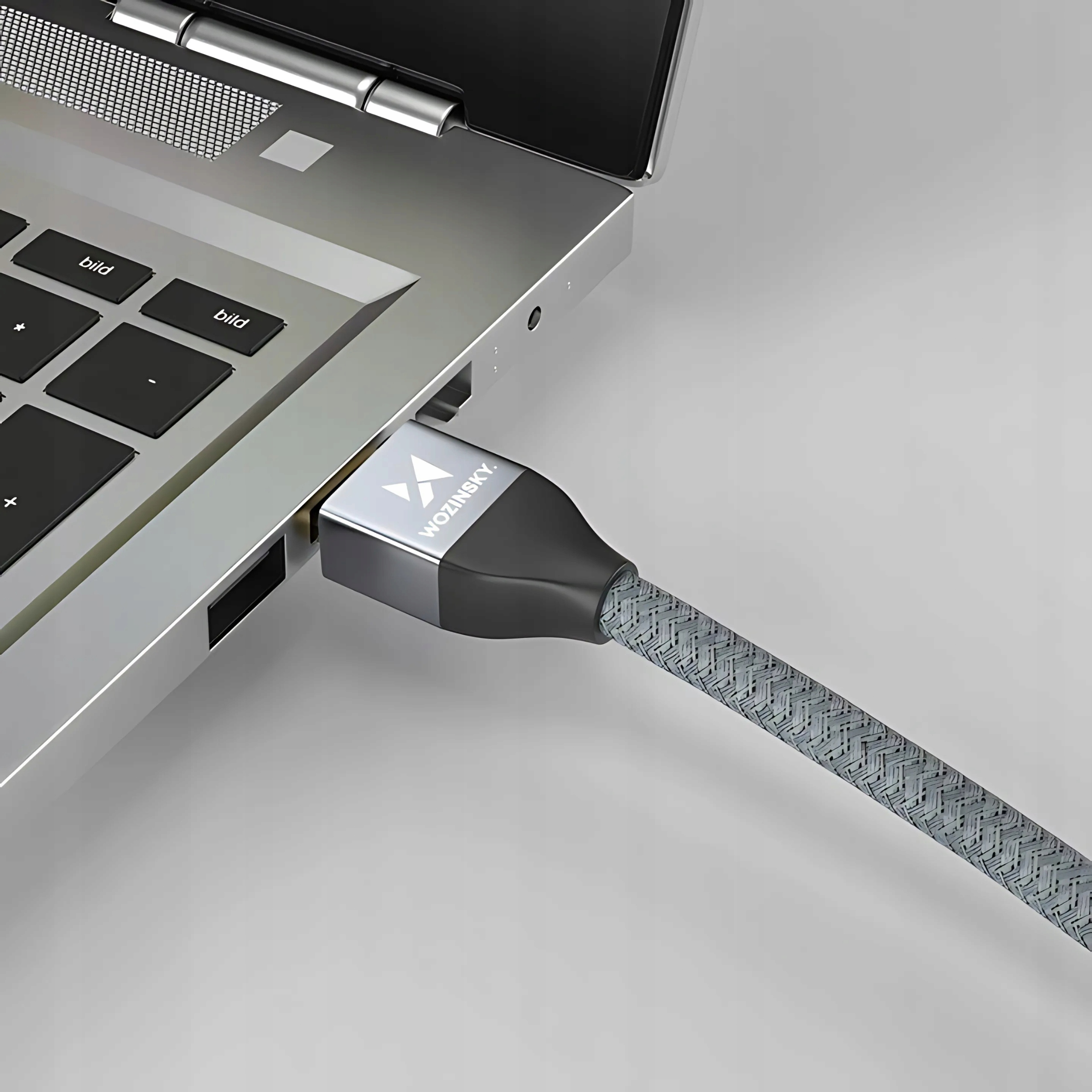 Kabel HDMI podłączony do laptopa. Kabel szary, laptop srebrny.