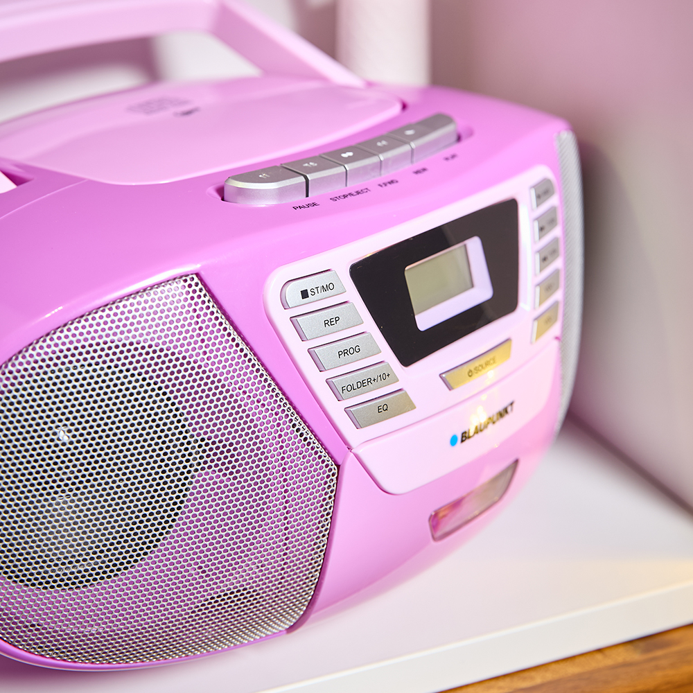 Pinkfarbene Boombox auf einem weißen Regal. Knöpfe und ein Bildschirm sind sichtbar.