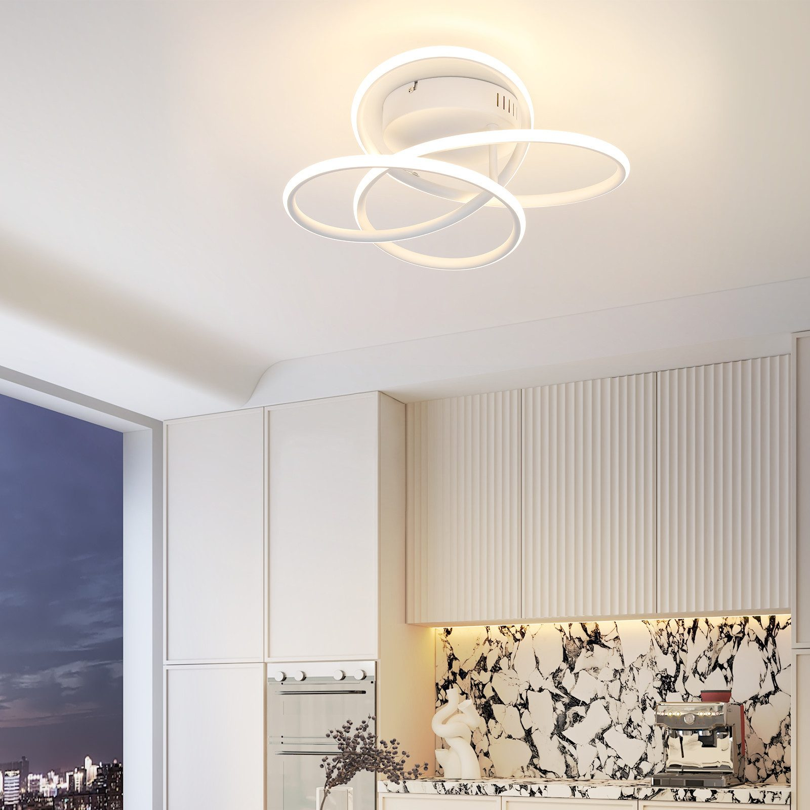 Una lampada da soffitto bianca con tre anelli intrecciati, installata in una cucina con mobili bianchi.