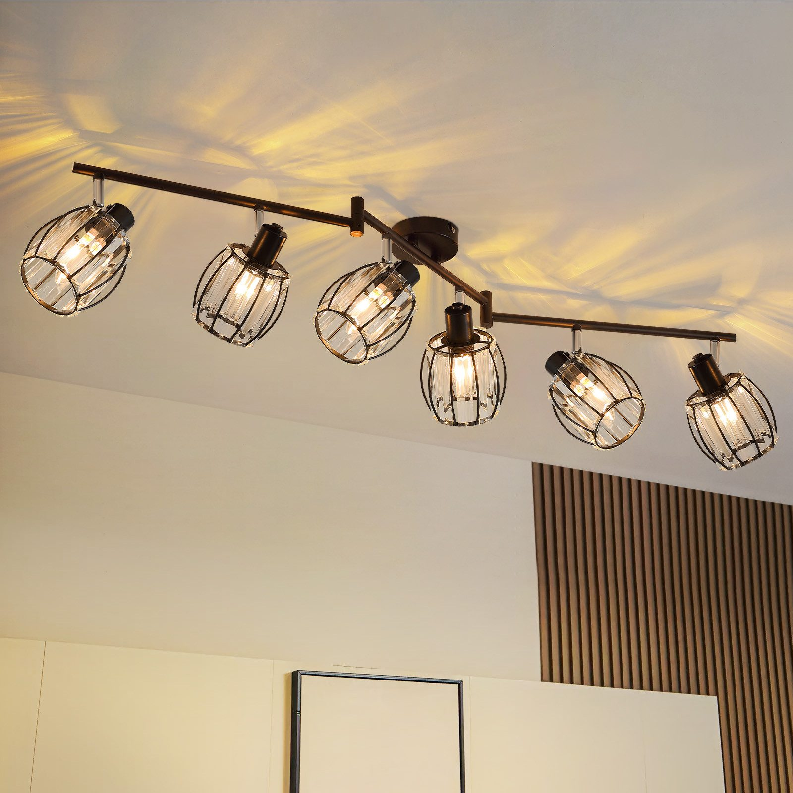 Un lampadario con sei lampadine racchiuse in vetro su una guida nera, in una stanza.