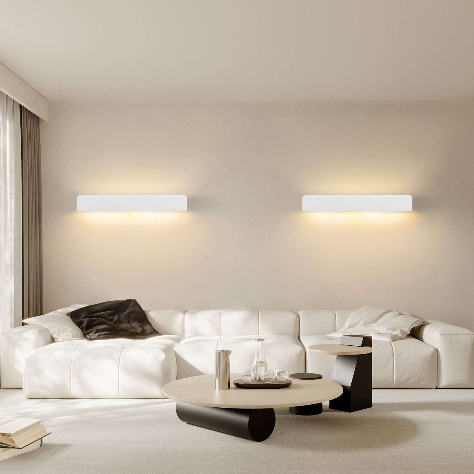 Un soggiorno luminoso con un divano bianco, due lampade da parete e un tavolino rotondo su un tappeto.