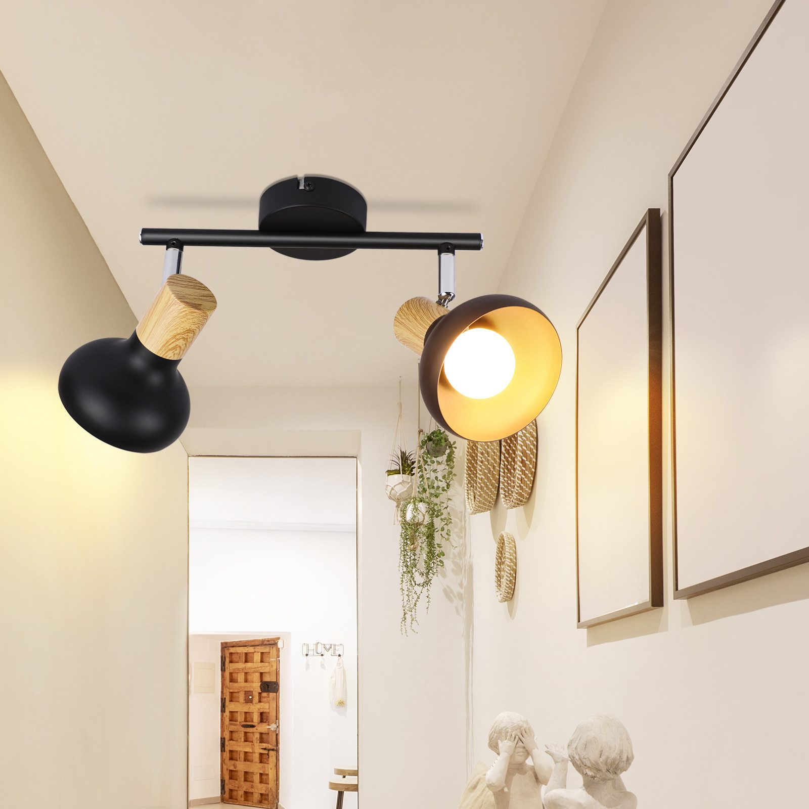 Corridoio con una lampada nera a due luci, opere d'arte e oggetti decorativi su una consolle.