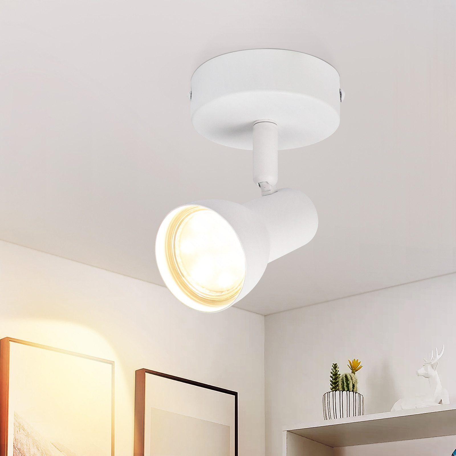 Un faretto bianco montato su un soffitto bianco con una mensola decorativa sotto.