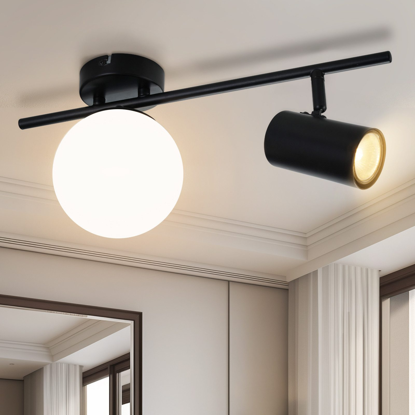 Una lampada da binario nera con paralume sferico e faretto cilindrico a soffitto.
