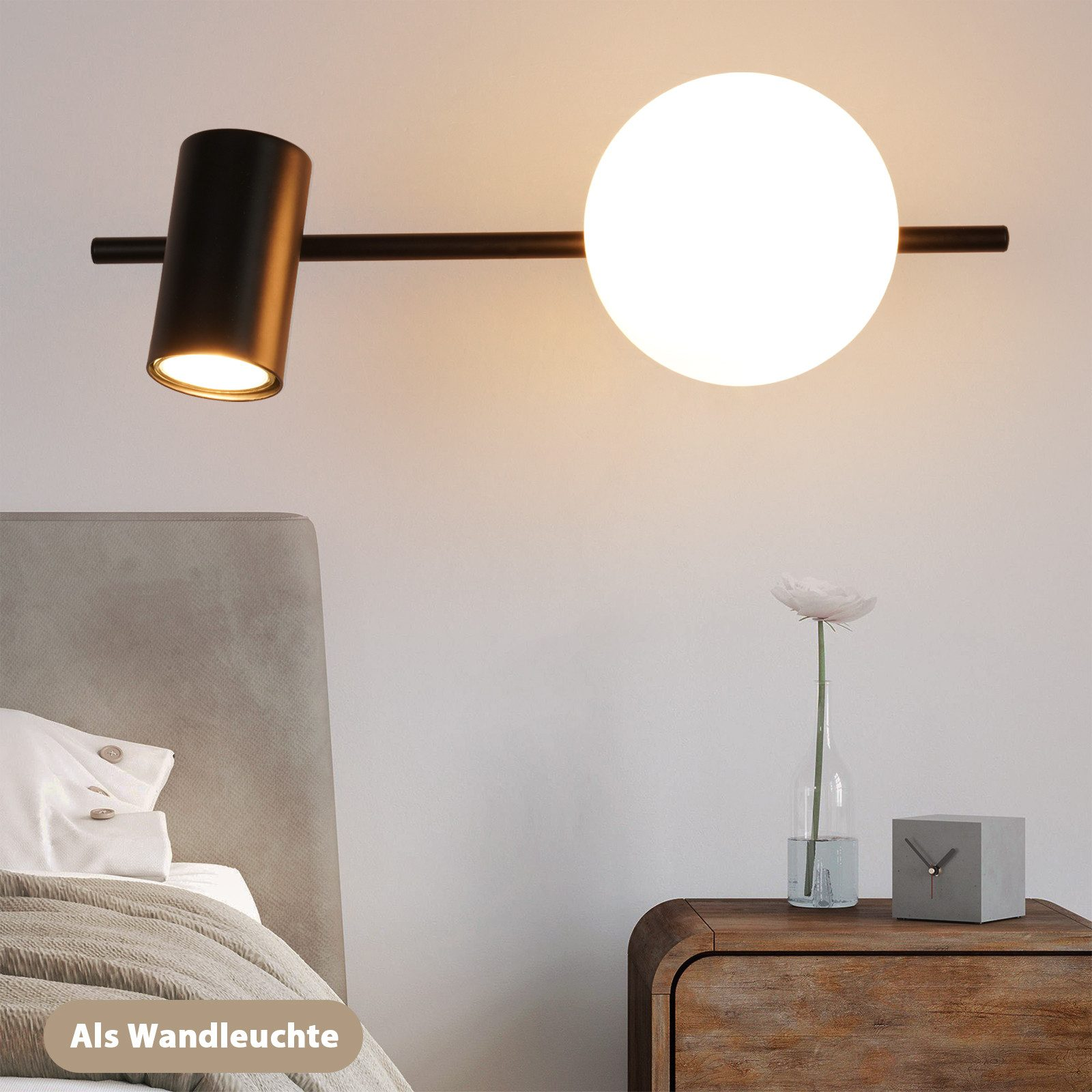Una lampada da binario nera con un globo e un faretto, montata sopra un comodino.
