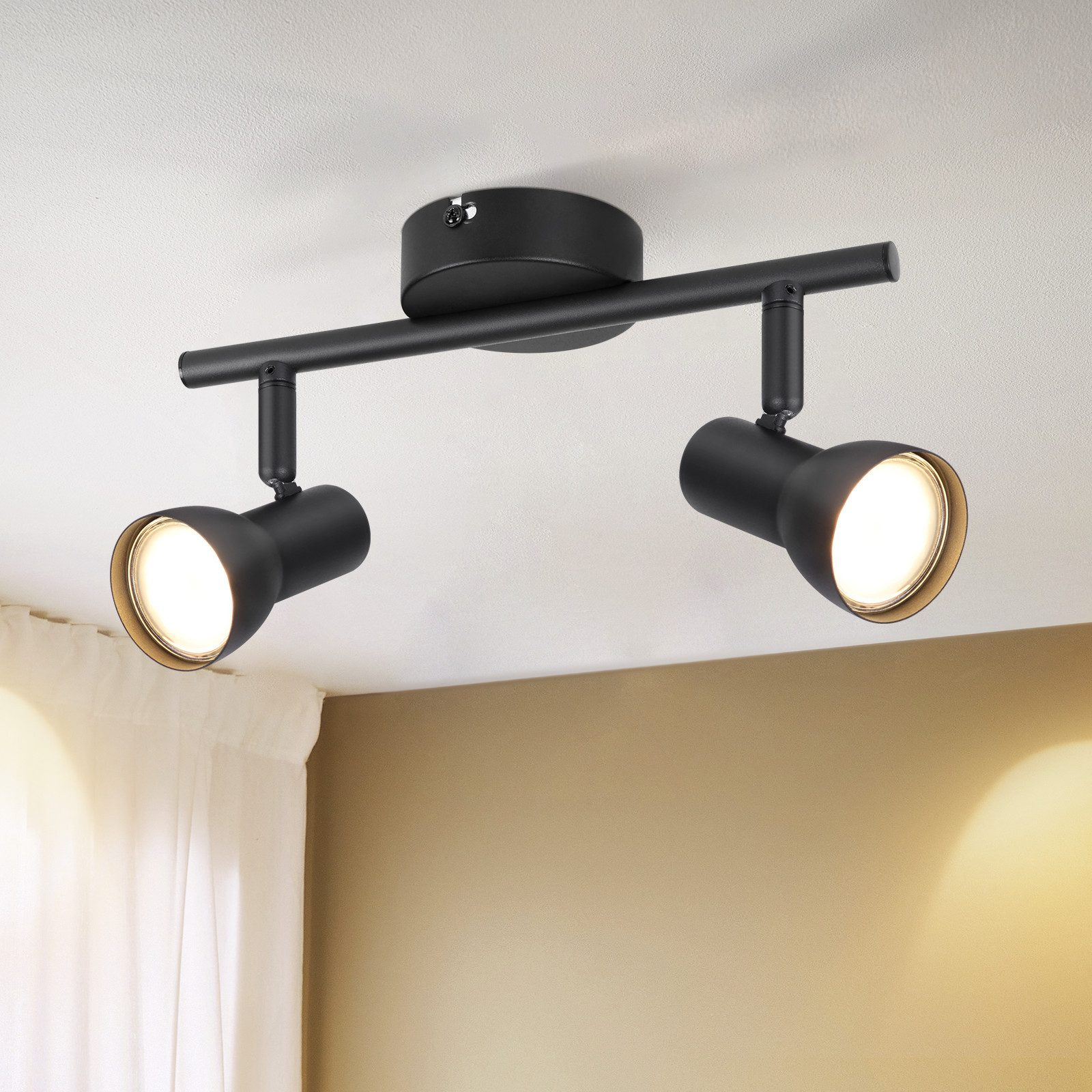 Una plafoniera nera con due faretti. Le luci sono rivolte verso il basso, illuminando il soffitto.