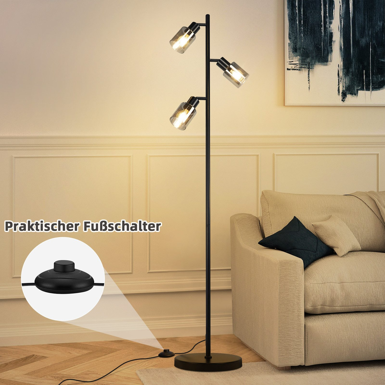 Czarna lampa podłogowa z trzema światłami i przełącznikiem nożnym. W tle znajduje się sofa.