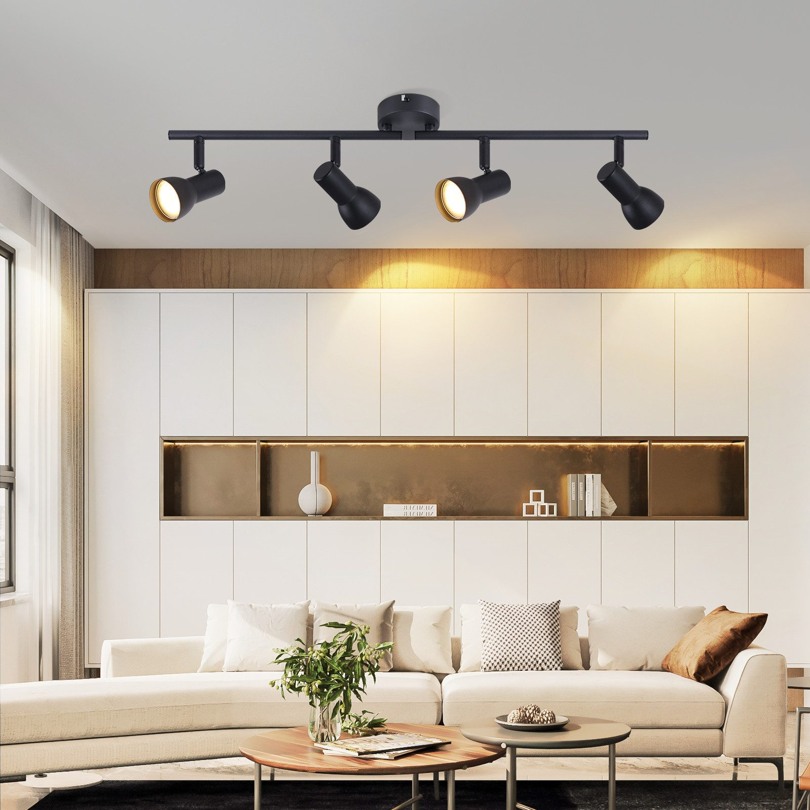 Quattro faretti neri su una barra nera, montati su un soffitto bianco, illuminano un soggiorno moderno.