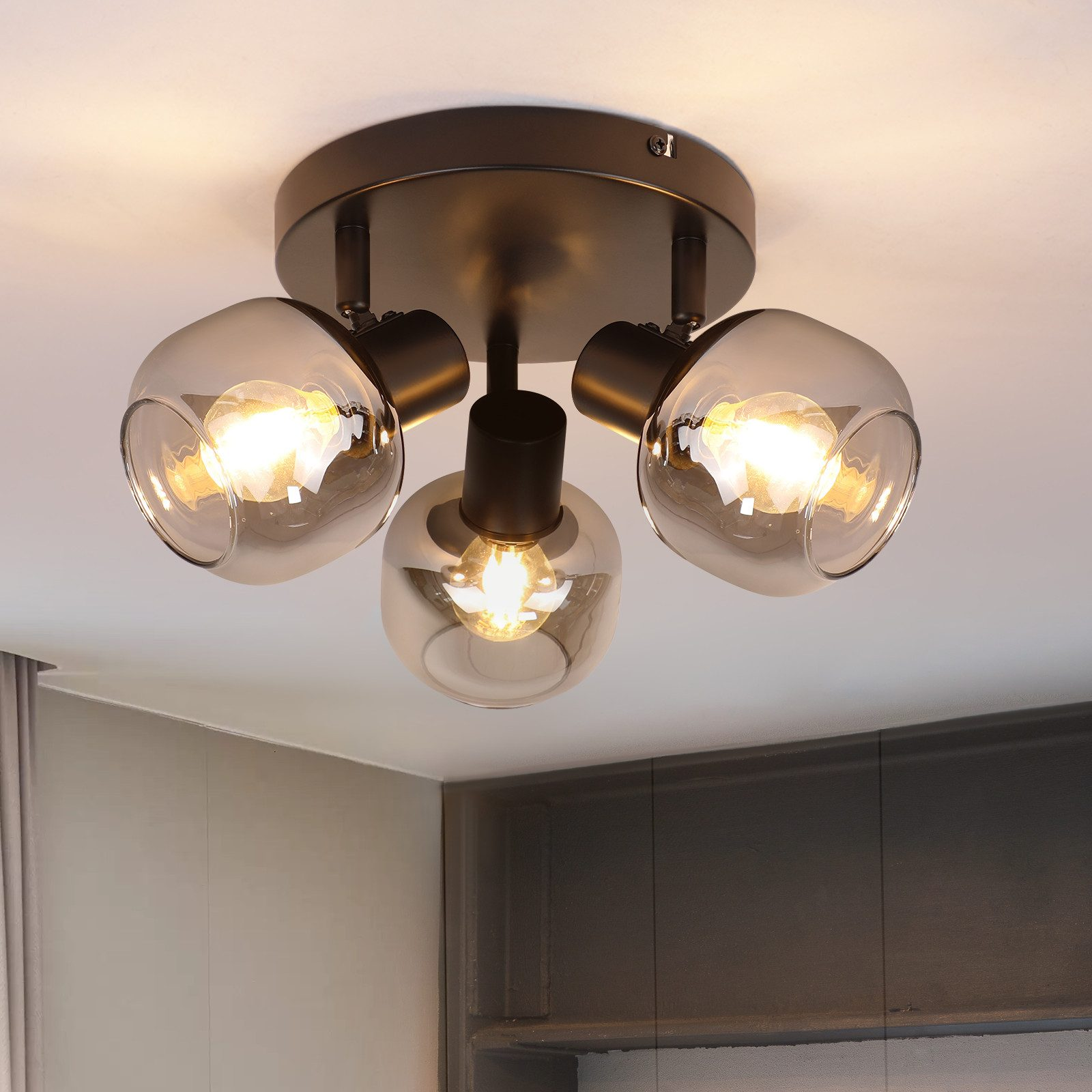 Luci a soffitto con tre lampadine di vetro. Ogni lampadina ha una luce che brilla all'interno. Il soffitto è bianco.