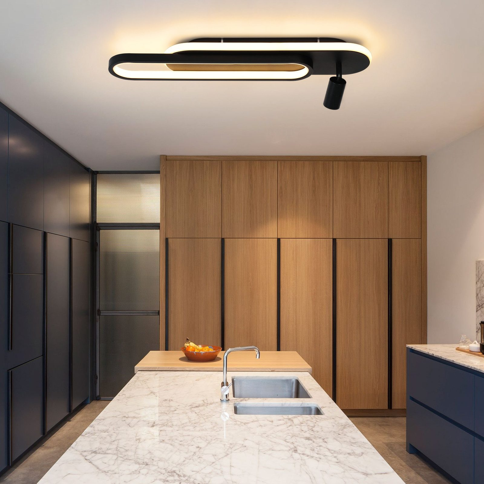 Nowoczesna lampa sufitowa nad marmurowym blatem w kuchni. Widoczne szafki i inne elementy kuchenne.