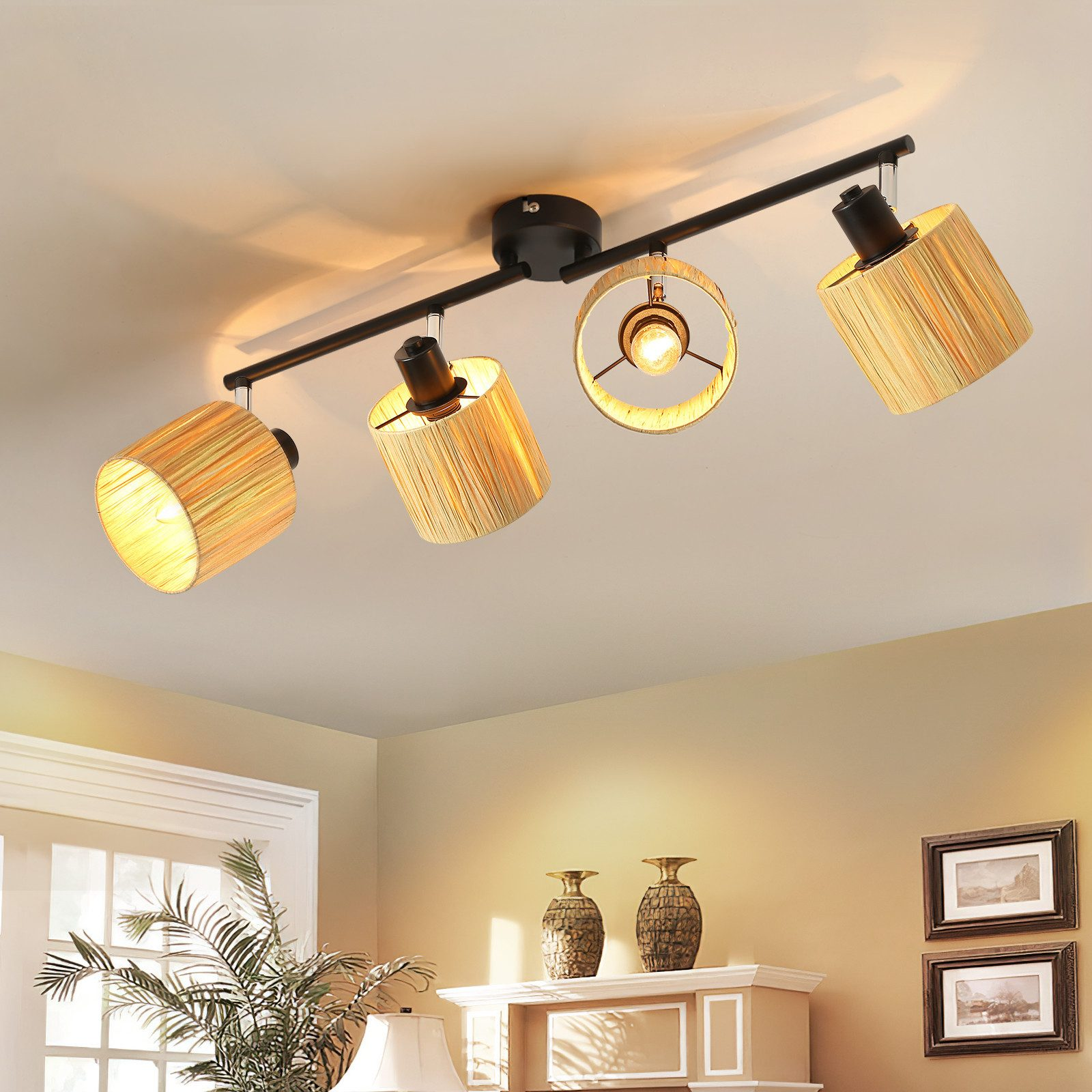 Un soffitto con un apparecchio di illuminazione nero con quattro paralumi. La stanza ha un soffitto bianco e pareti beige.