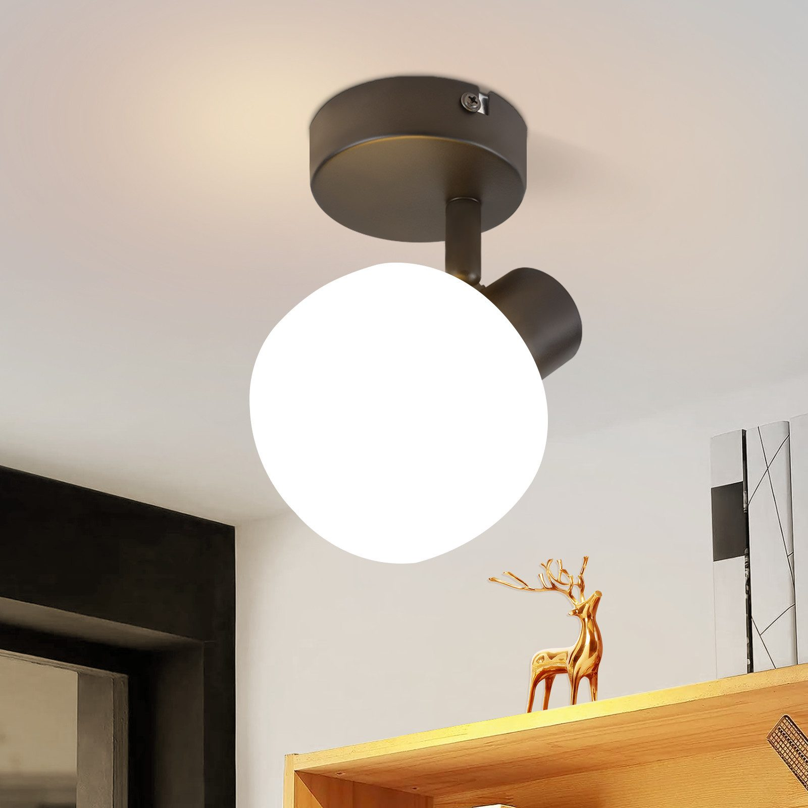 Una moderna plafoniera con paralume rotondo bianco. È montata su un'apparecchiatura scura contro un soffitto bianco.