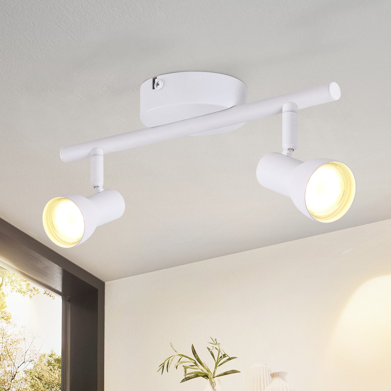 Una plafoniera bianca con due faretti è montata sul soffitto. C'è un vaso con fiori.