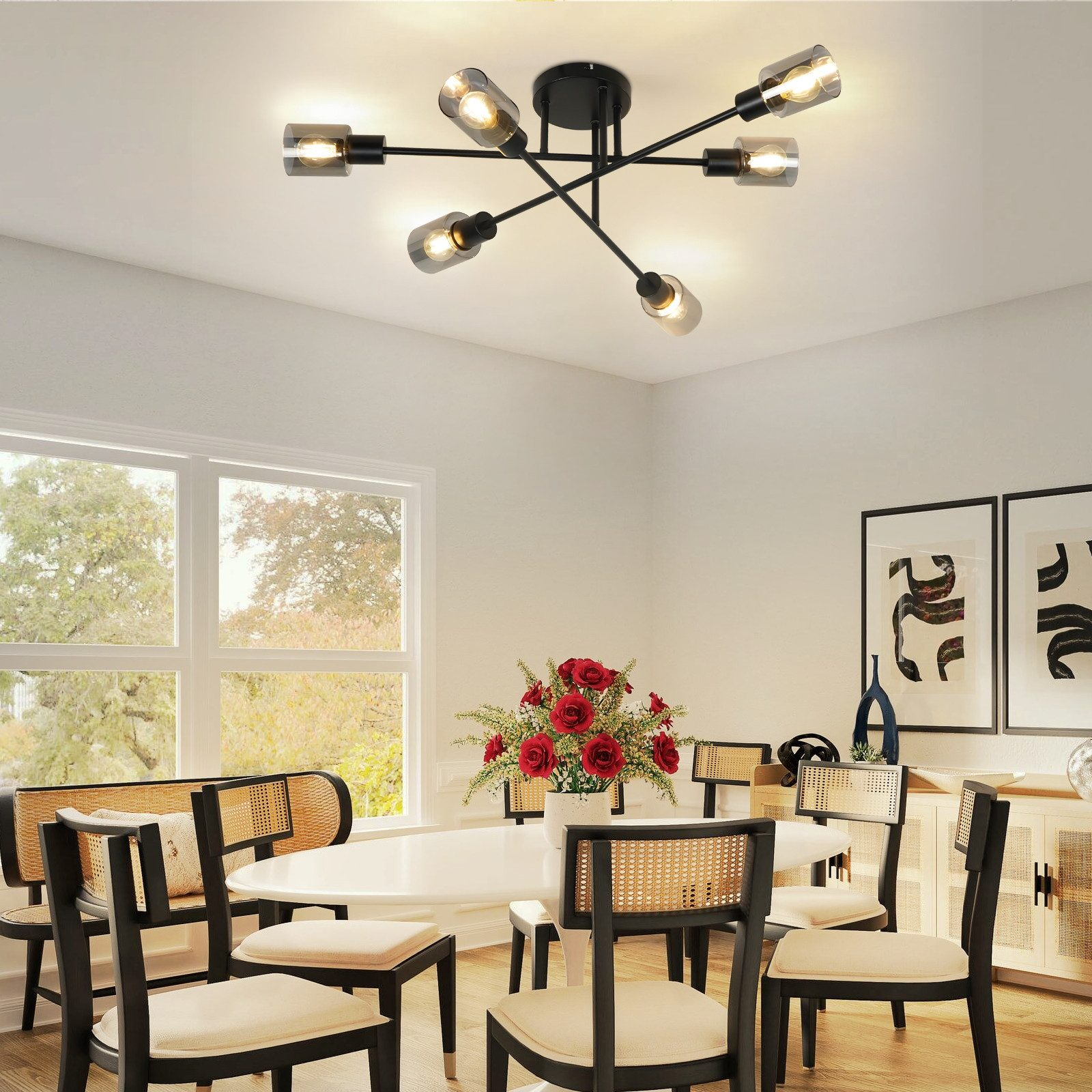Sala da pranzo con una moderna lampada da soffitto. Tavolo e sedie bianche. Rose rosse e arte sulla parete.