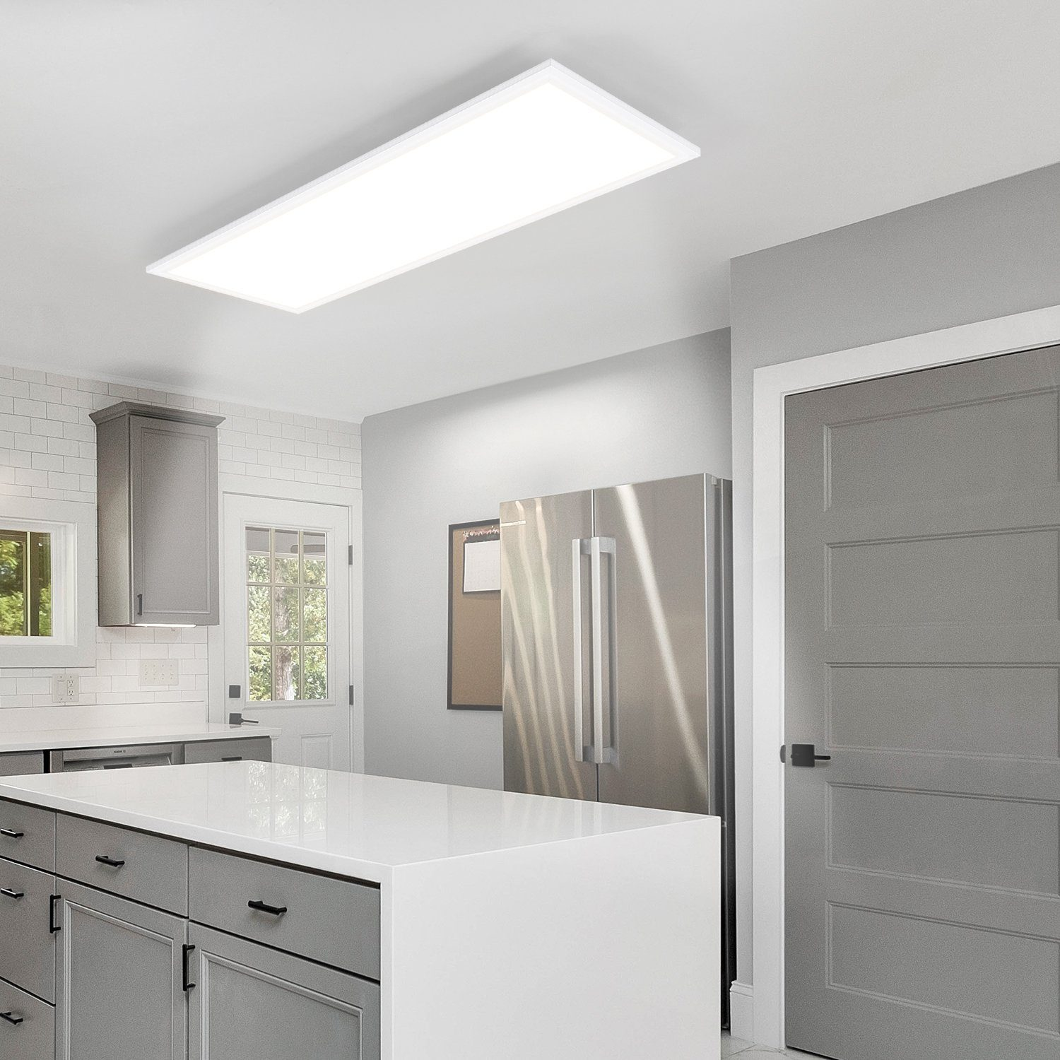Una cucina moderna con una plafoniera LED rettangolare, un'isola e elettrodomestici in acciaio inossidabile.