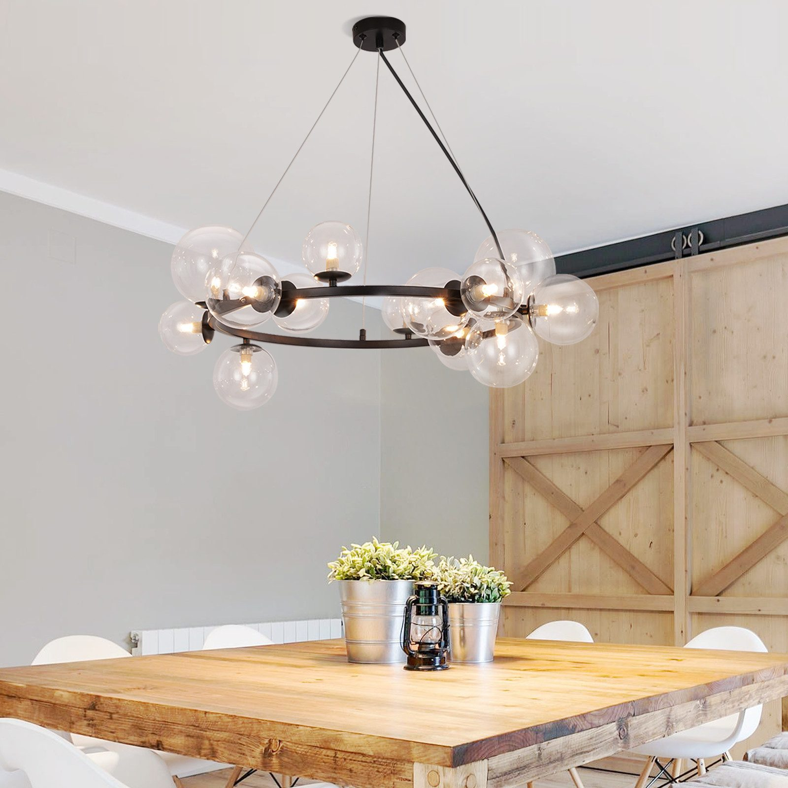 Una sala da pranzo con un tavolo in legno, secchi di metallo con piante e un lampadario con sfere di vetro.