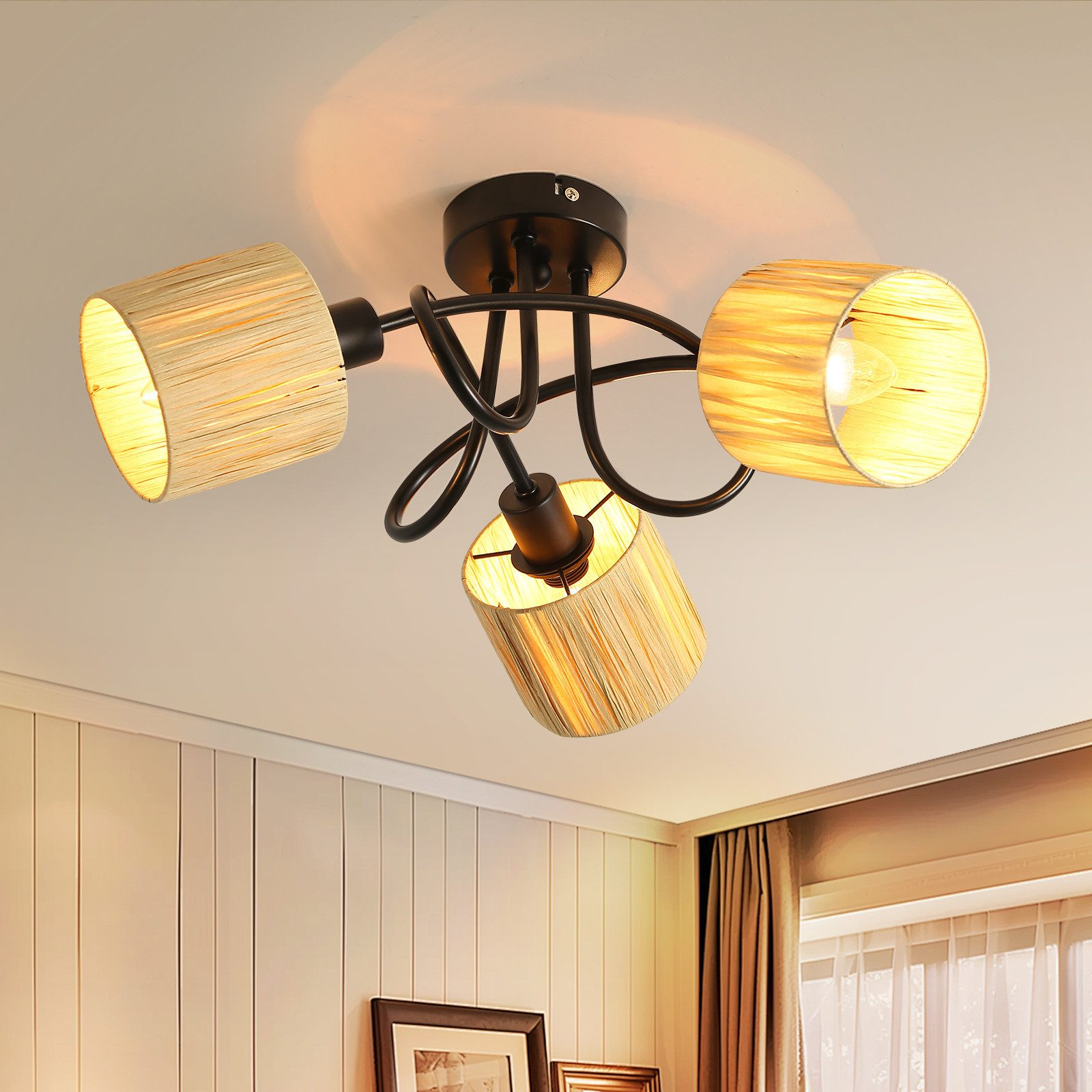 Una plafoniera con tre paralumi intrecciati, montata su un soffitto con modanature e una finestra sullo sfondo.