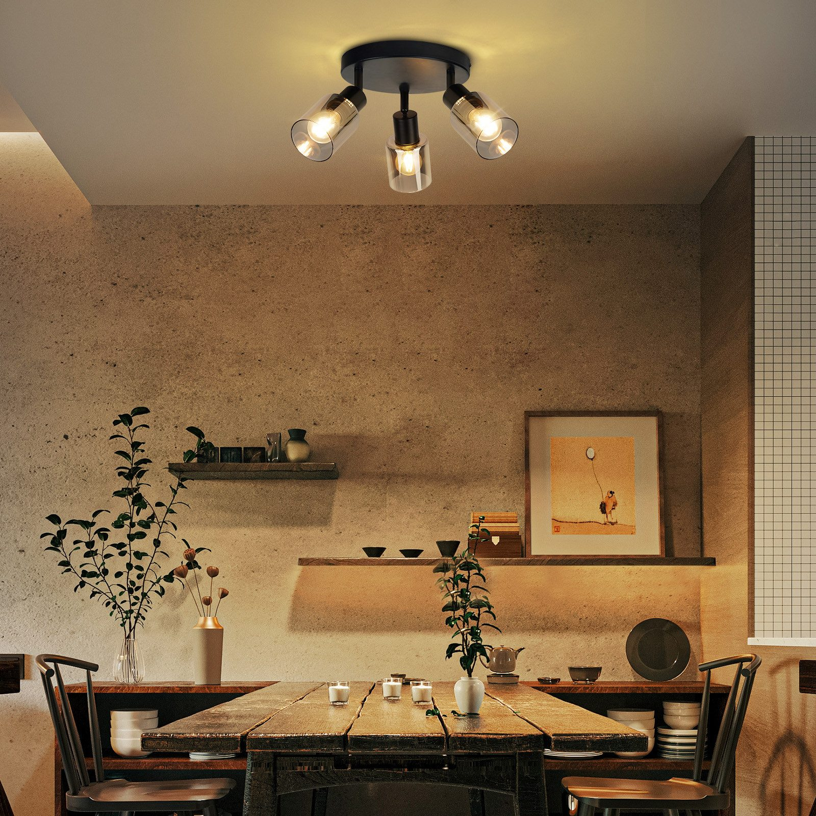 Una sala da pranzo presenta un tavolo apparecchiato sotto una plafoniera a tre lampadine, creando un'atmosfera calda.