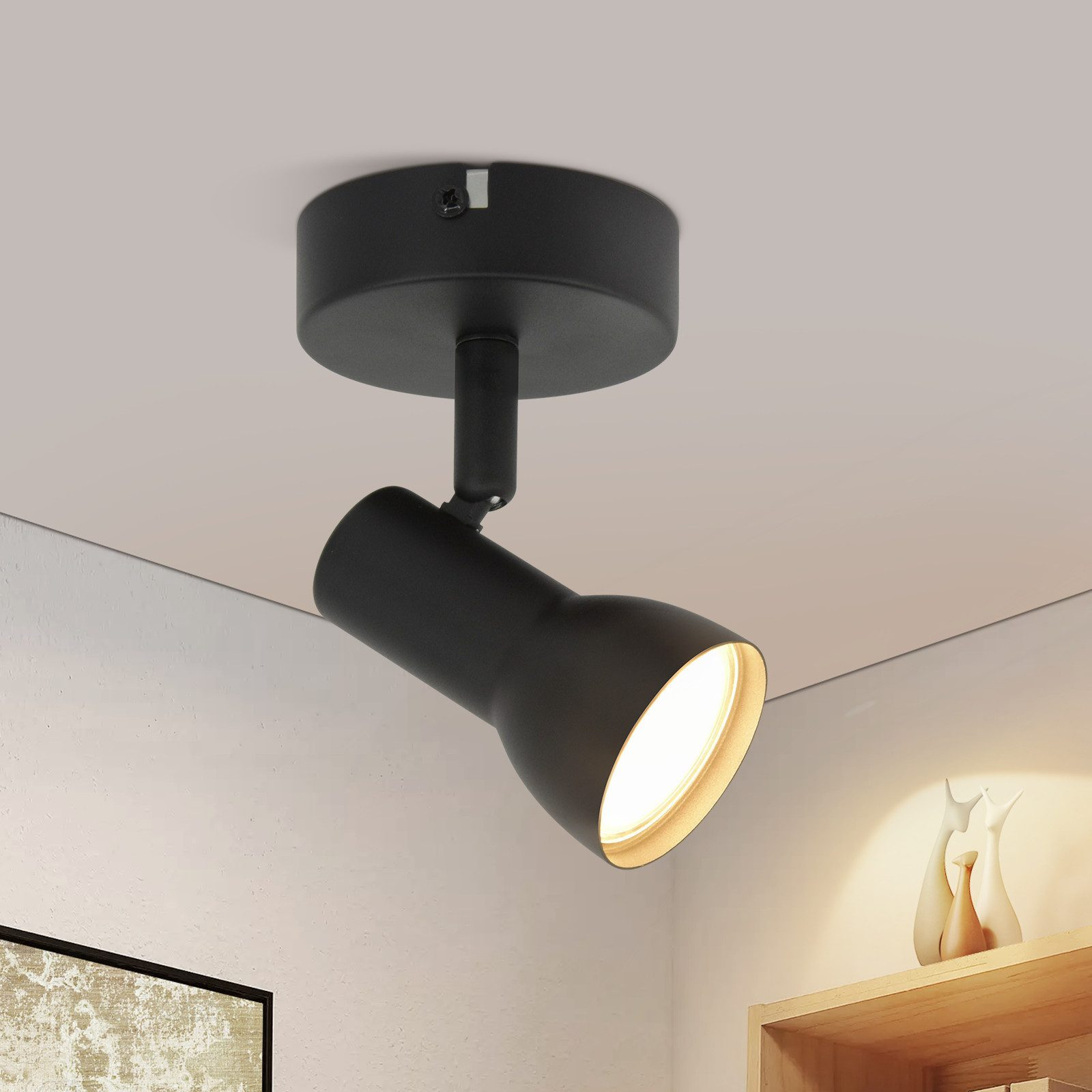 Un faretto nero illumina una stanza con pareti bianche e decorazioni.