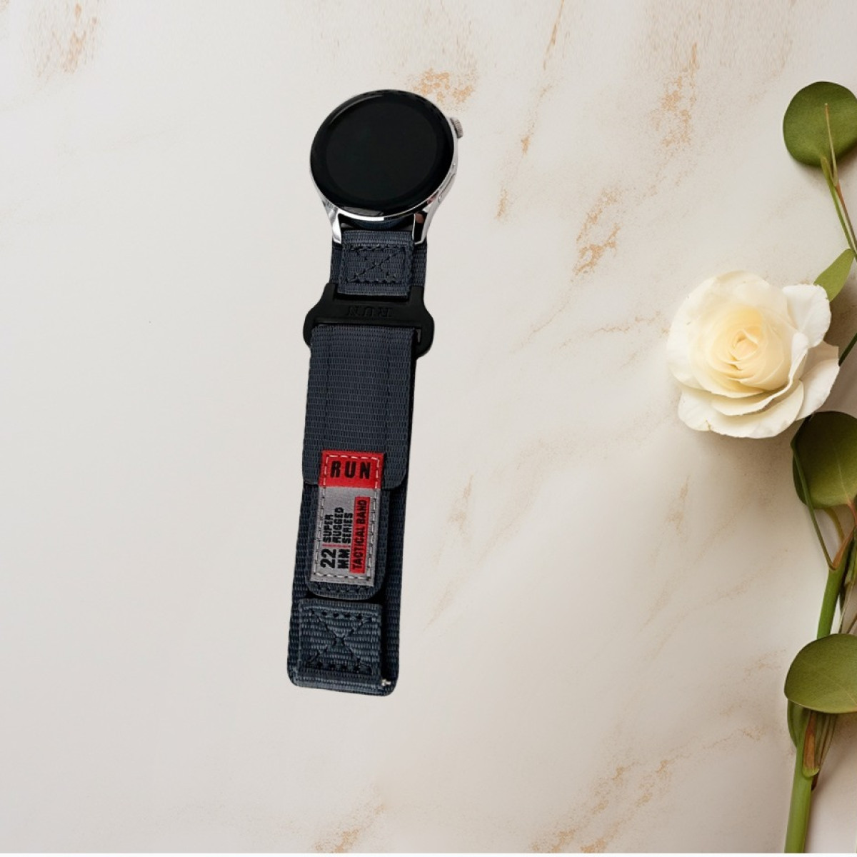 Eine graue Uhr mit einem Nylonarmband wird mit einer Blume und Blättern angezeigt.