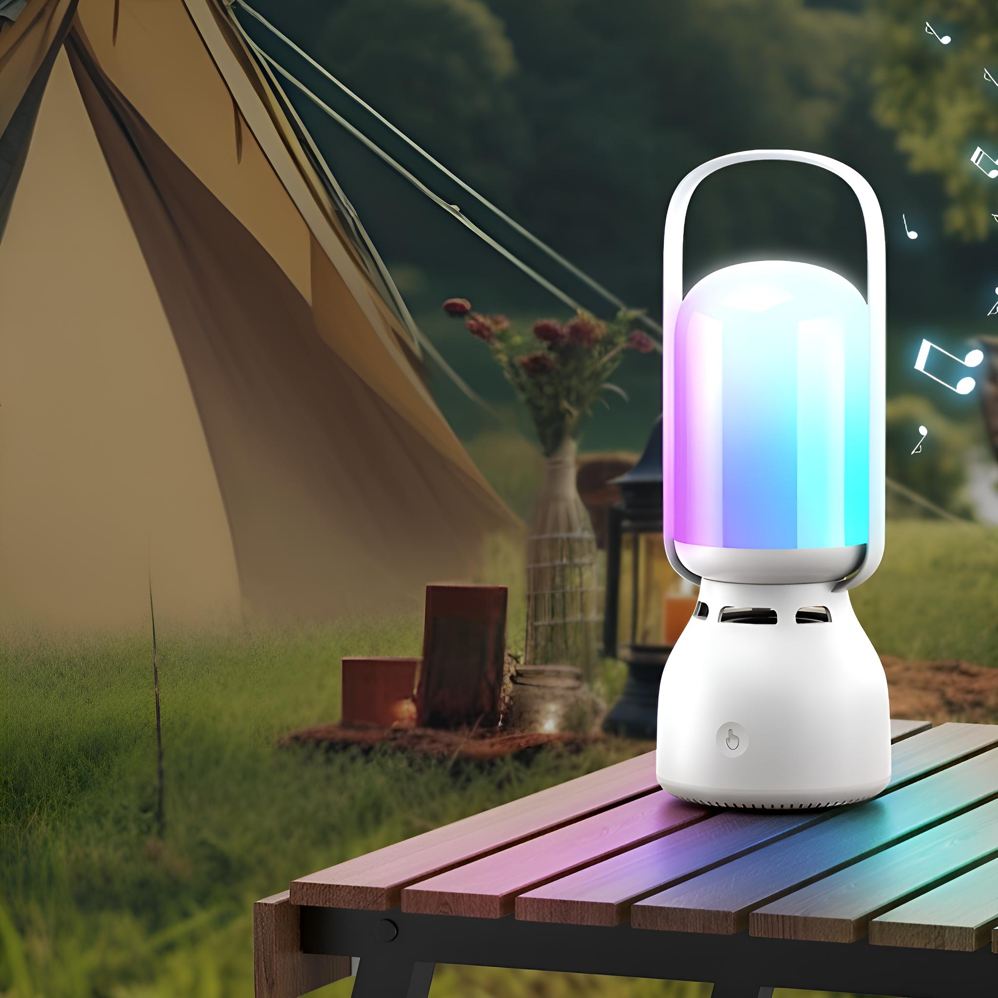 Ein tragbarer Lautsprecher mit buntem Licht steht auf einem Holztisch in der Nähe eines Zeltes.