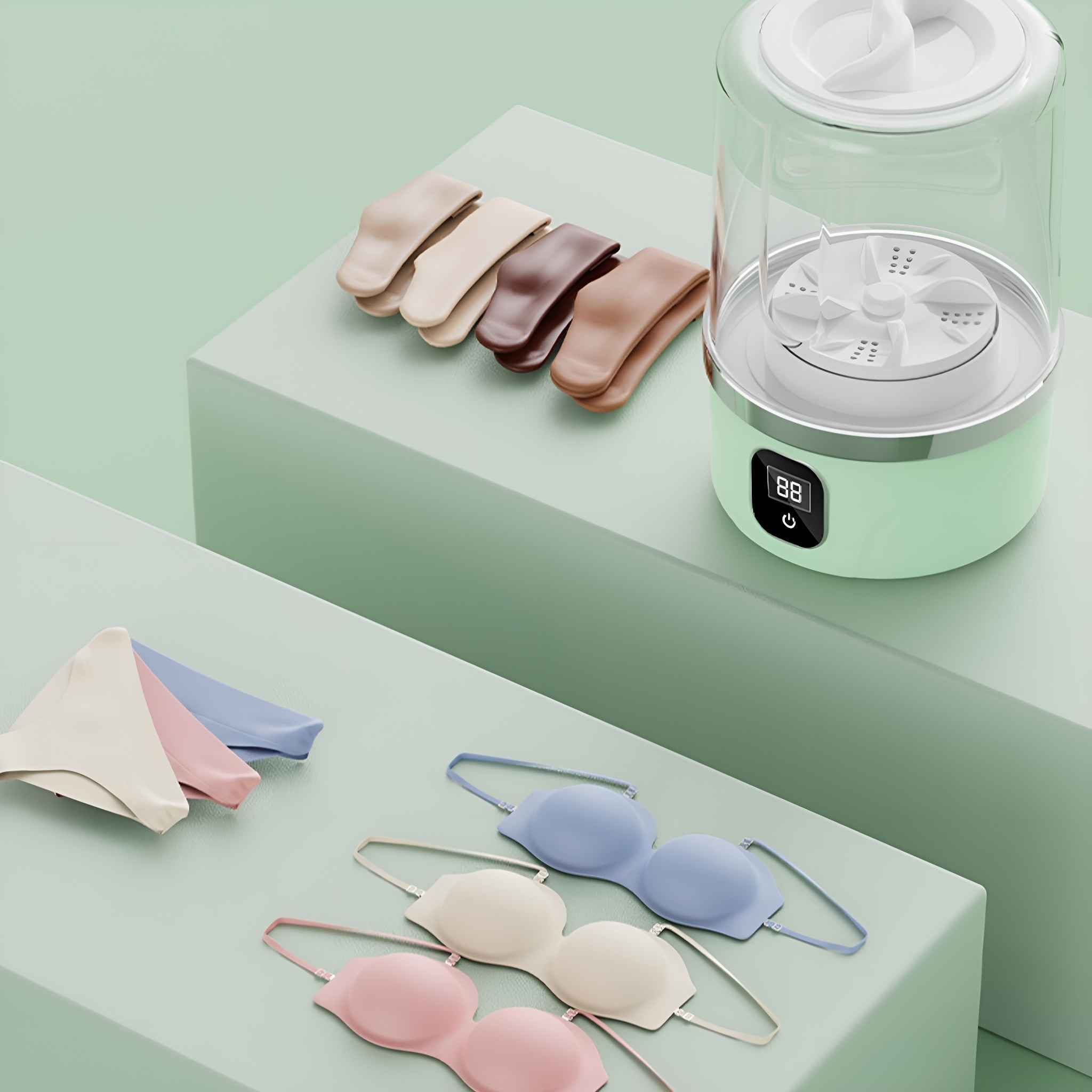 Kleine, grüne Mini-Waschmaschine mit ausgestellter Lingerie. Artikel auf mintgrünen Plattformen angeordnet.