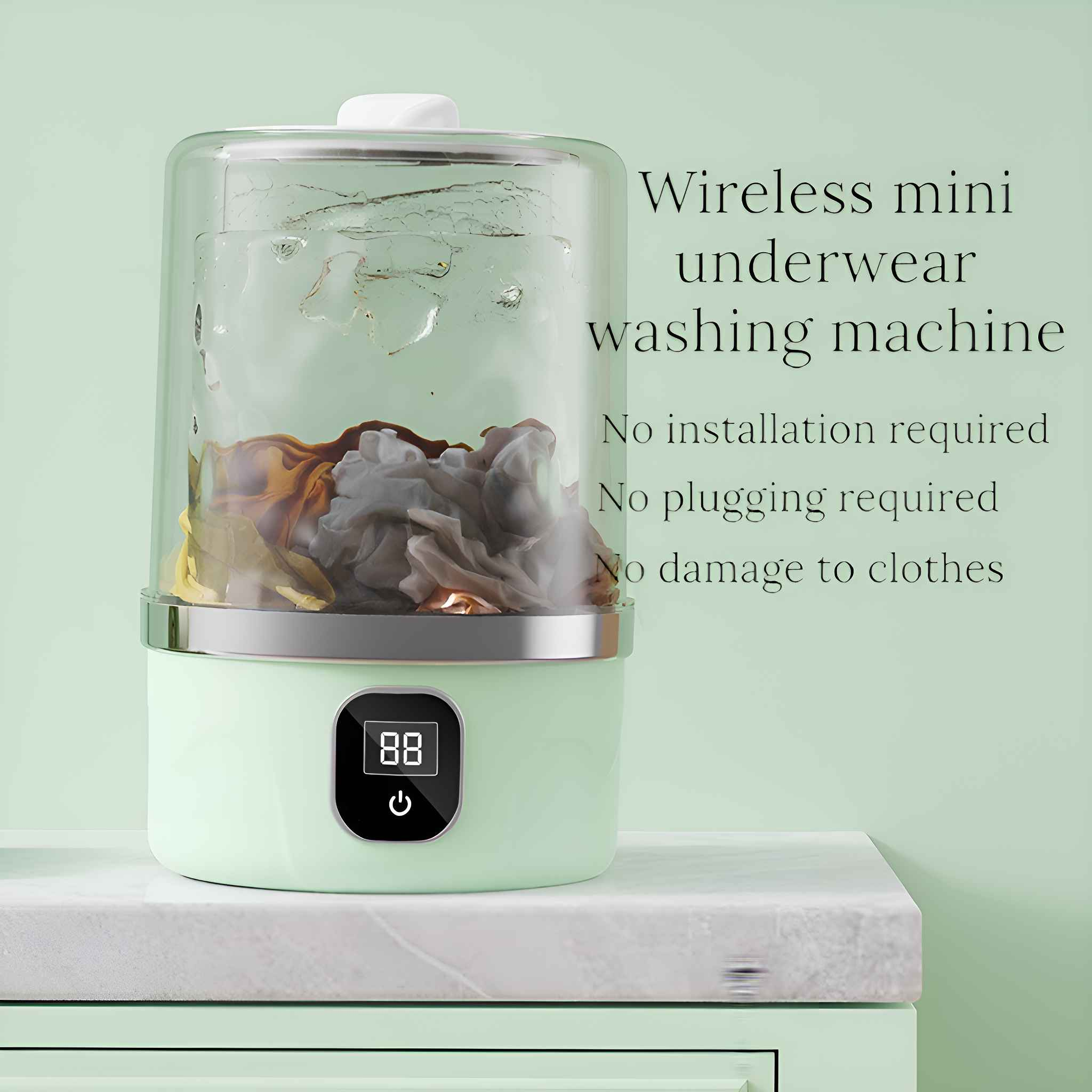 Kleine, grüne Mini-Waschmaschine mit durchsichtigem Oberteil, gefüllt mit Wasser und Kleidung. Auf einer weißen Theke.