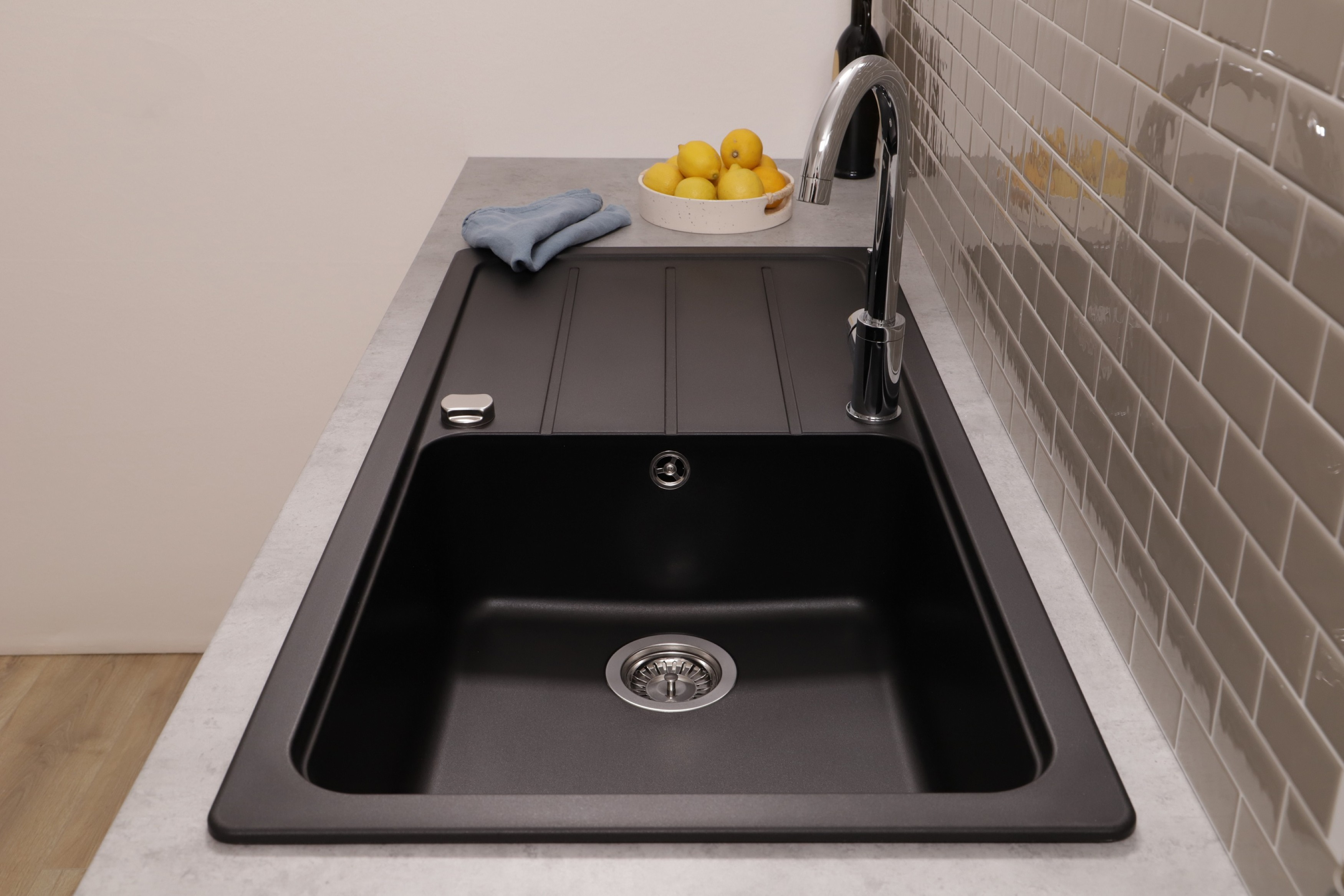 Un lavello da cucina nero con rubinetto cromato è mostrato in un ambiente cucina.