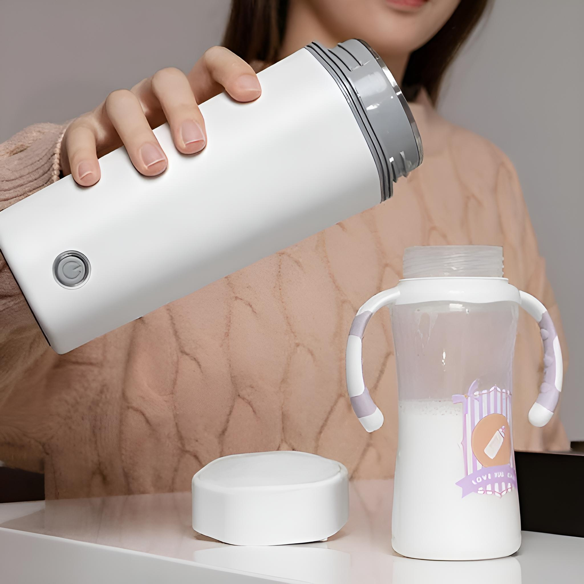 Eine Person gießt Flüssigkeit aus einer weißen Thermoskanne in eine Babyflasche auf einer weißen Oberfläche.