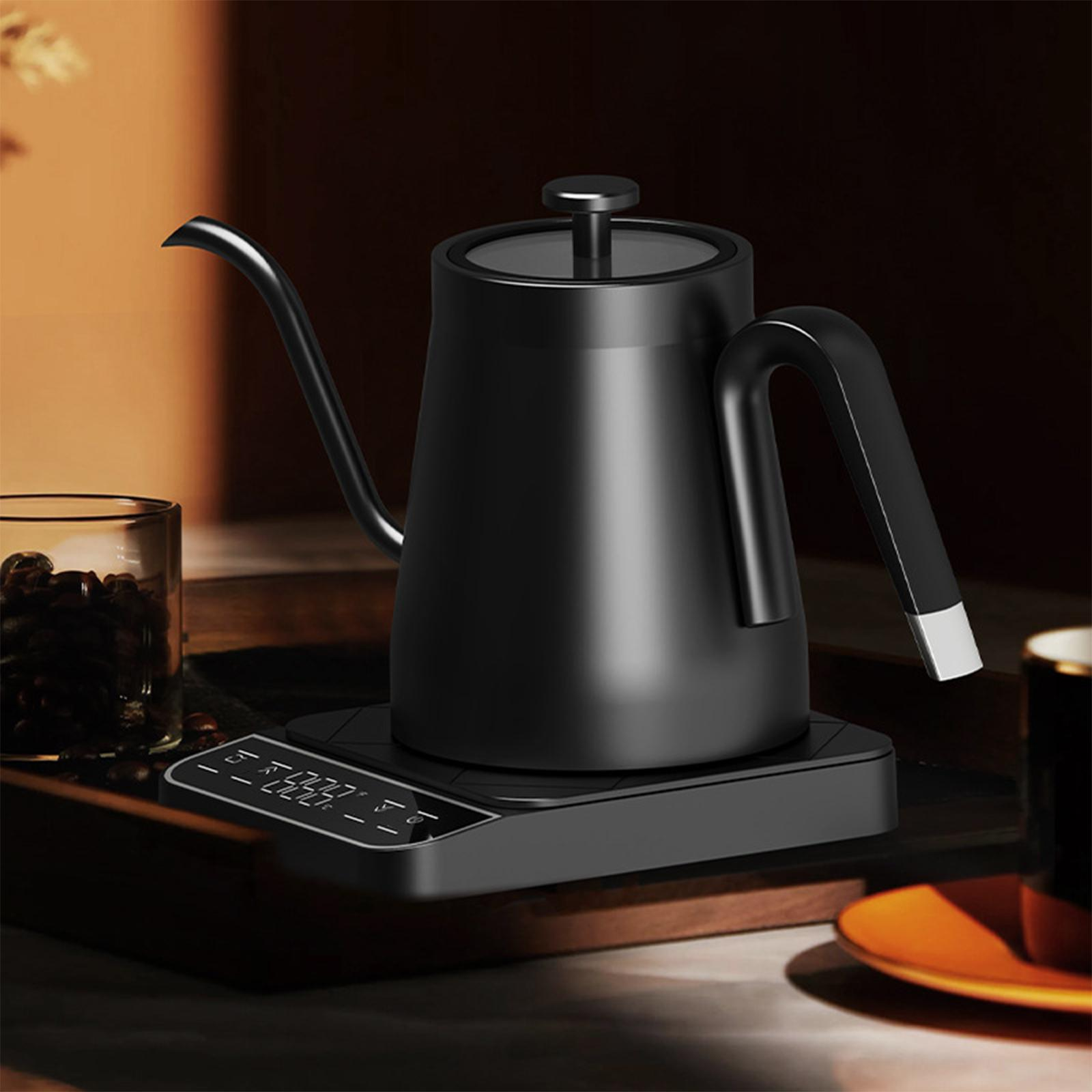 Ein schwarzer Schwanenhalskessel steht auf einer digitalen Basis, mit einer Tasse Kaffeebohnen und einem Teller in der Nähe.