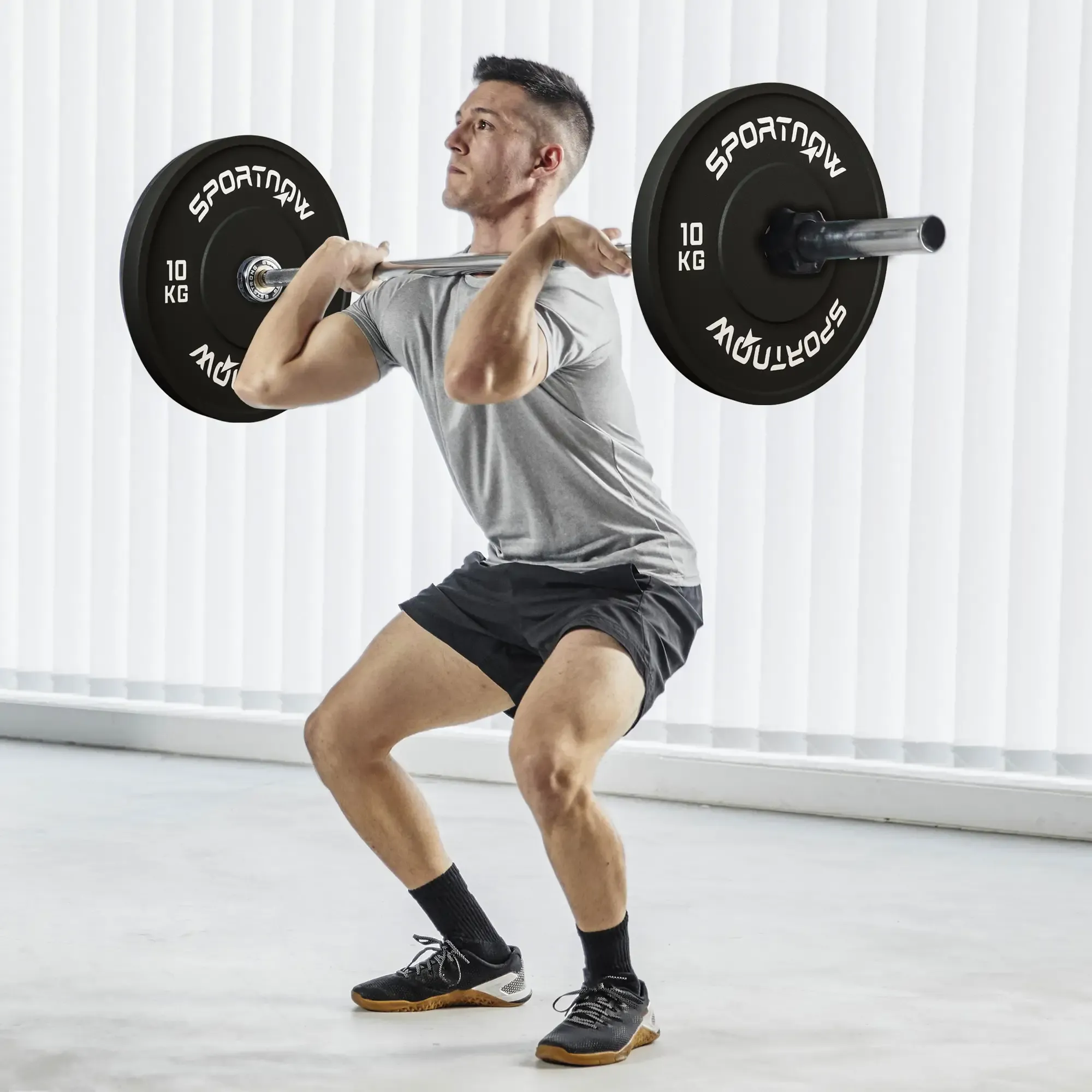 Mann hebt eine Langhantel mit schwarzen Gewichtsscheiben in einem Fitnessstudio.