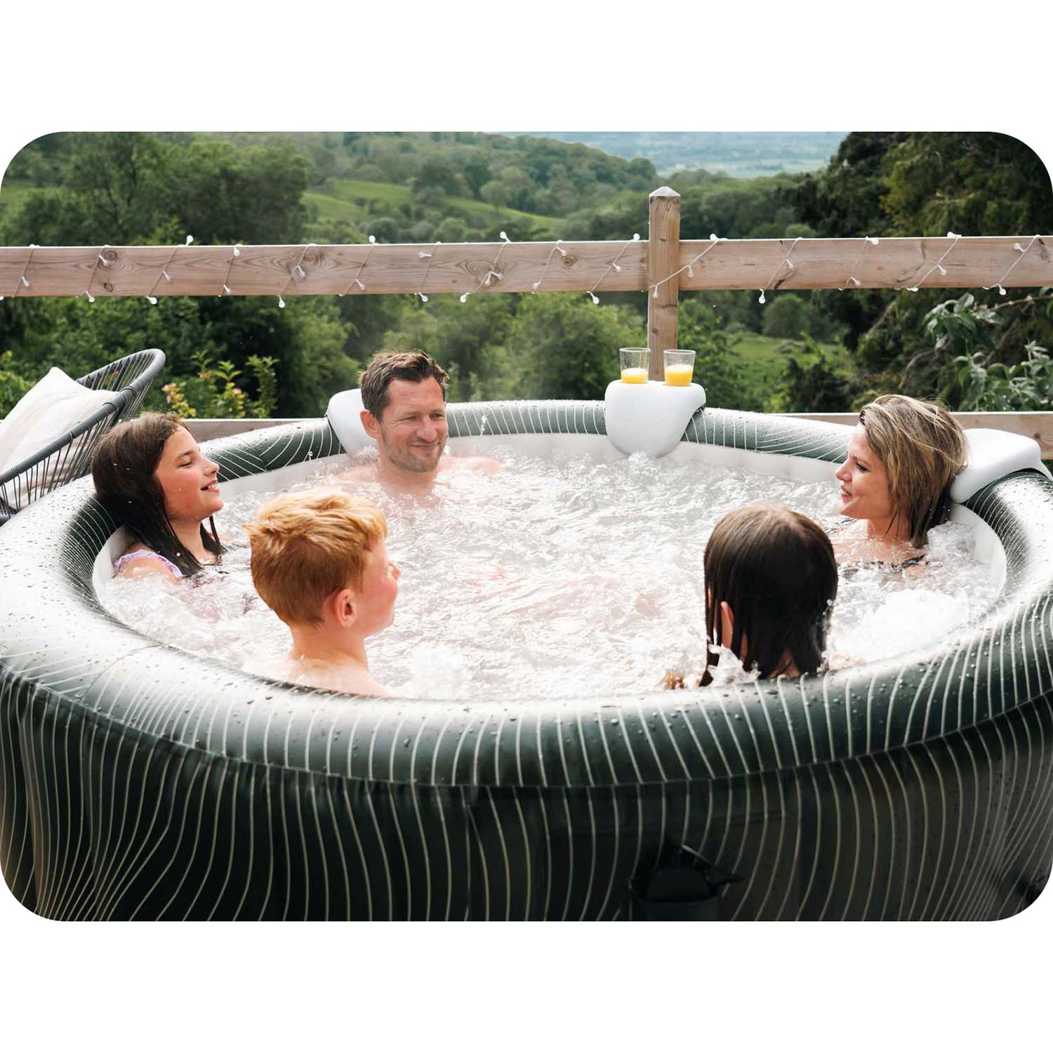 Grupa osób relaksuje się w wannie z hydromasażem, ciesząc się słonecznym dniem na świeżym powietrzu z napojami i rozmowami.