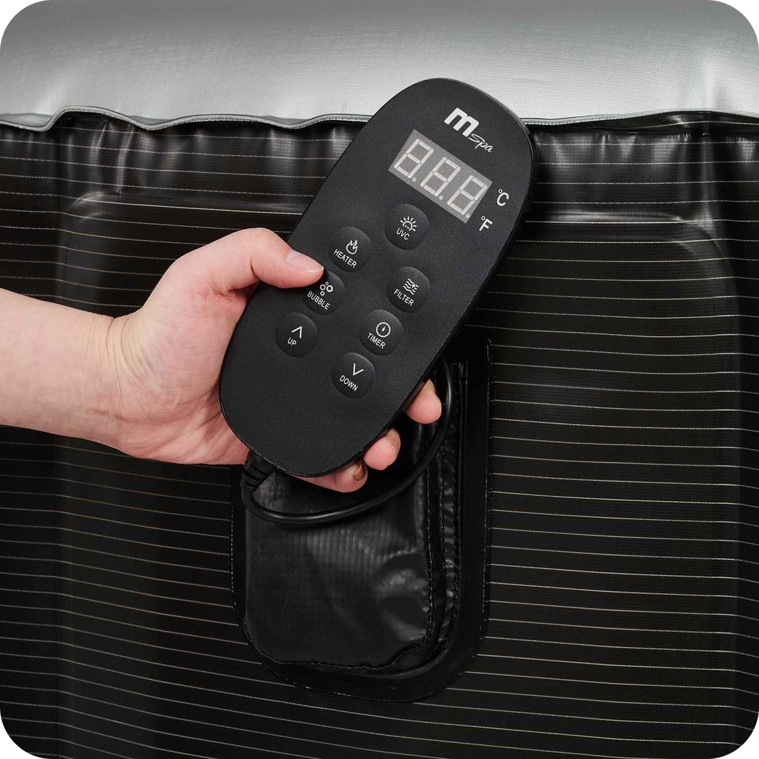 Ręka trzyma czarny pilot z różnymi przyciskami i wyświetlaczem cyfrowym.