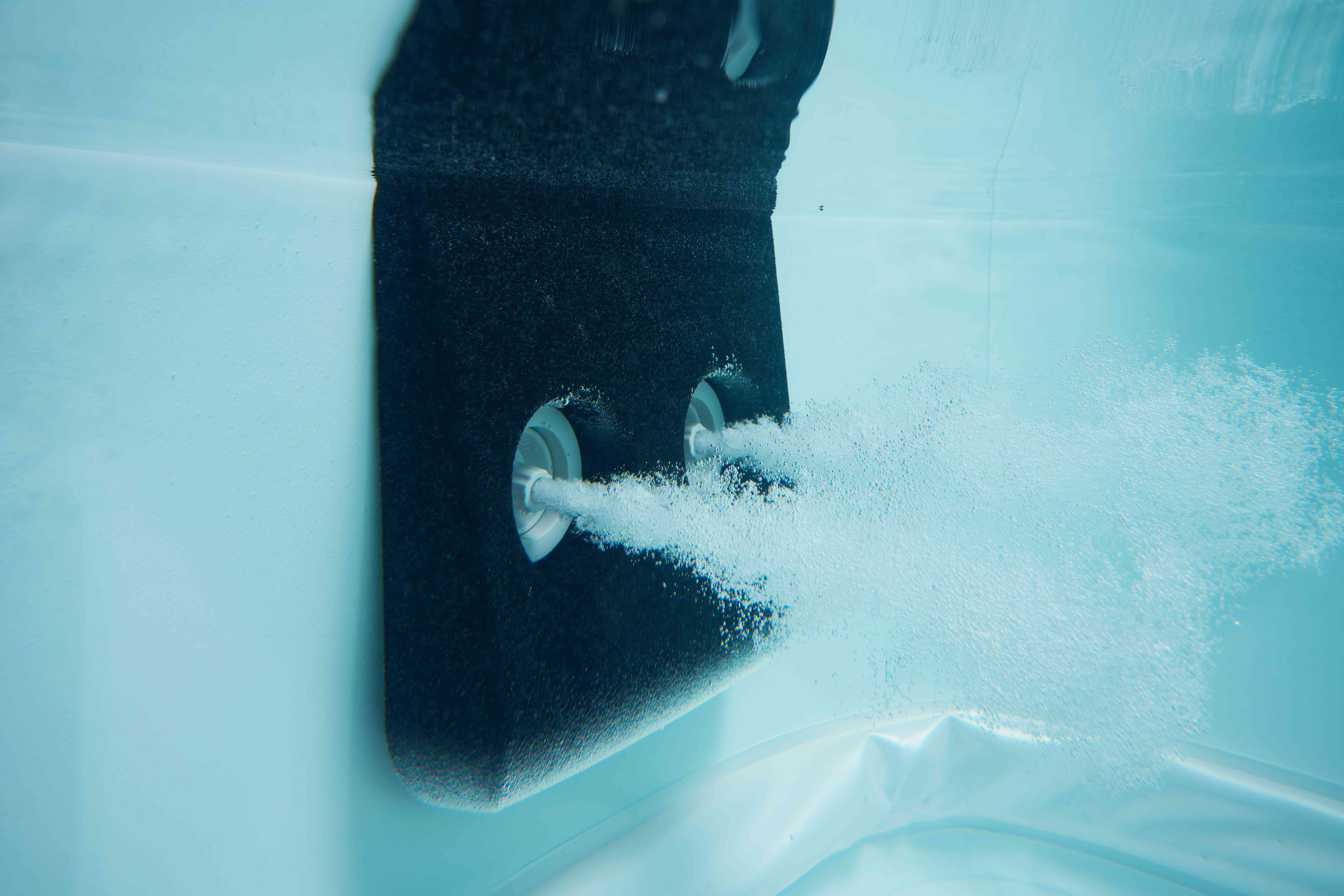 Podwodny widok dysz w wannie z hydromasażem uwalniających bąbelki do wody.