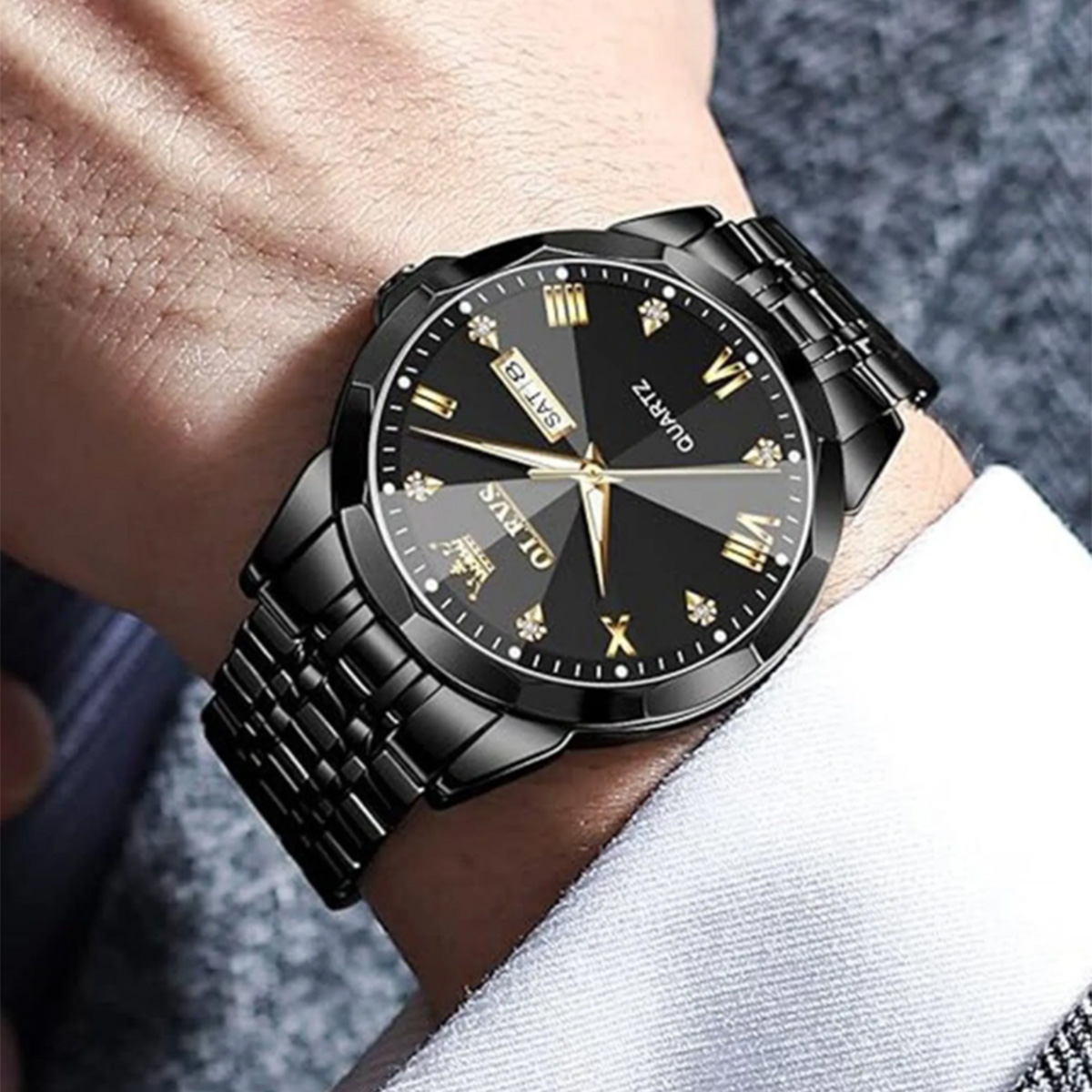 Eine schwarze OLEVS-Armbanduhr am Handgelenk einer Person, mit schwarzem Zifferblatt und silbernem Armband.